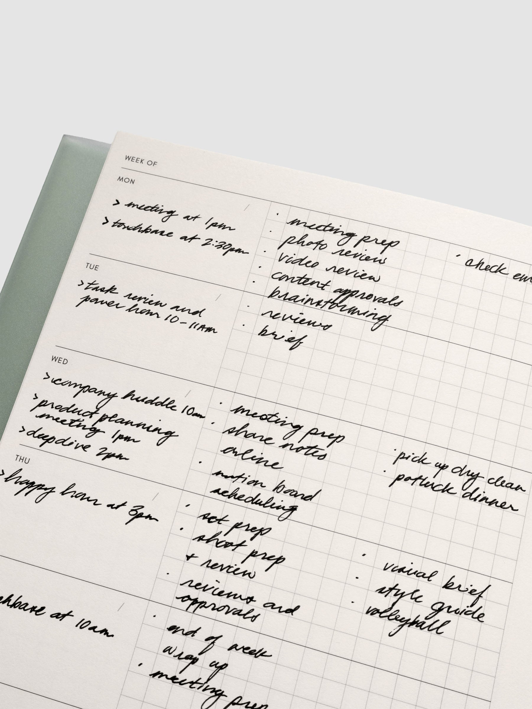 Close up of the Perfect Bound Notebook | A5 | Weekly Agenda | Matcha showing the horizontal weekly layout with blank space for notes, the date, and a graph notes section. There are handwritten examples of how to use the layout.