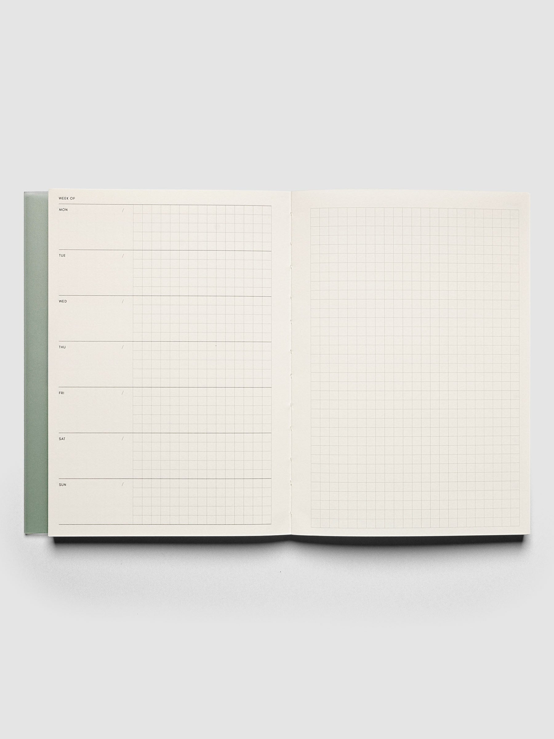 Perfect Bound Notebook | A5 | Weekly Agenda | Matcha shown open, laid flat, and on a neutral background. The left hand page has an undated horizontal weekly layout with blank space and graph note space for each day. The right hand page has a graph notes layout.