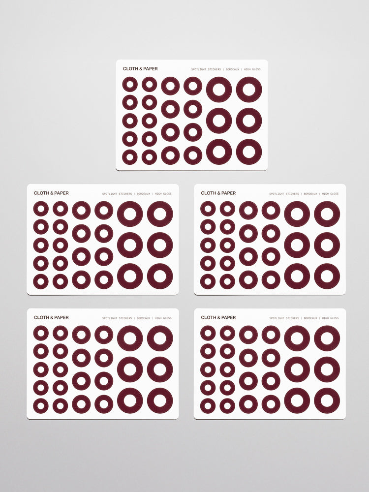 Five sticker sheets of burgundy (bordeaux) Spotlight Stickers | High Gloss on a neutral background.