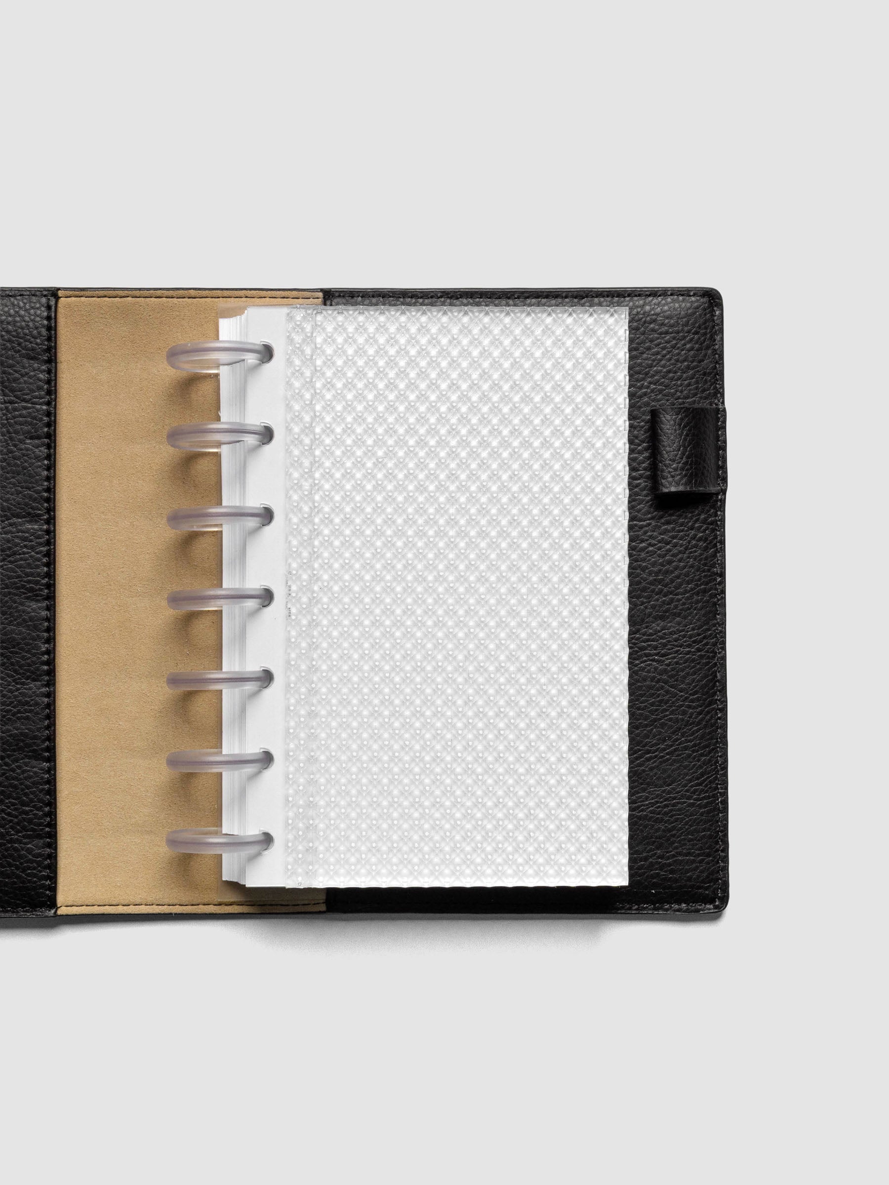 Clear, textured Studded Planner Dashboard in the size HP Mini, shown disbound in a black leather folio on a neutral background.