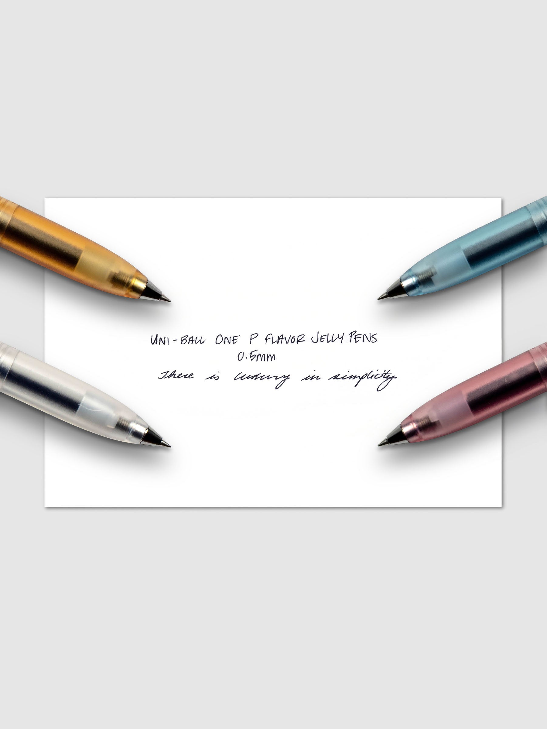 All four colors of the Uni-Ball One P Flavor Jelly Pen with a handwritten writing sample.