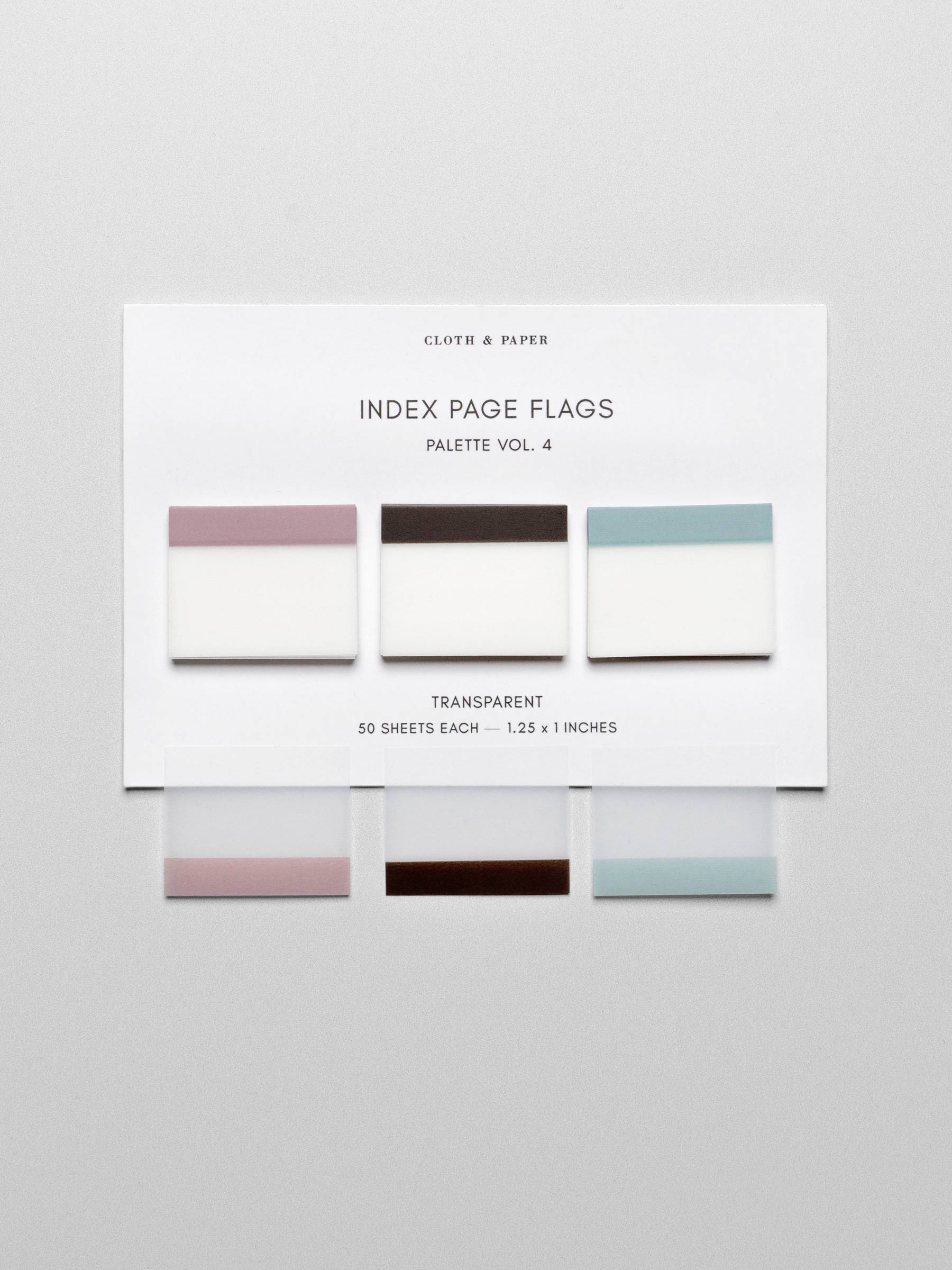 Set of three unique colors of transparent index page flags including pink, brown, and blue shown laying flat on backing card against a neutral background. One of each color is shown overlayed onto the background for true colors.