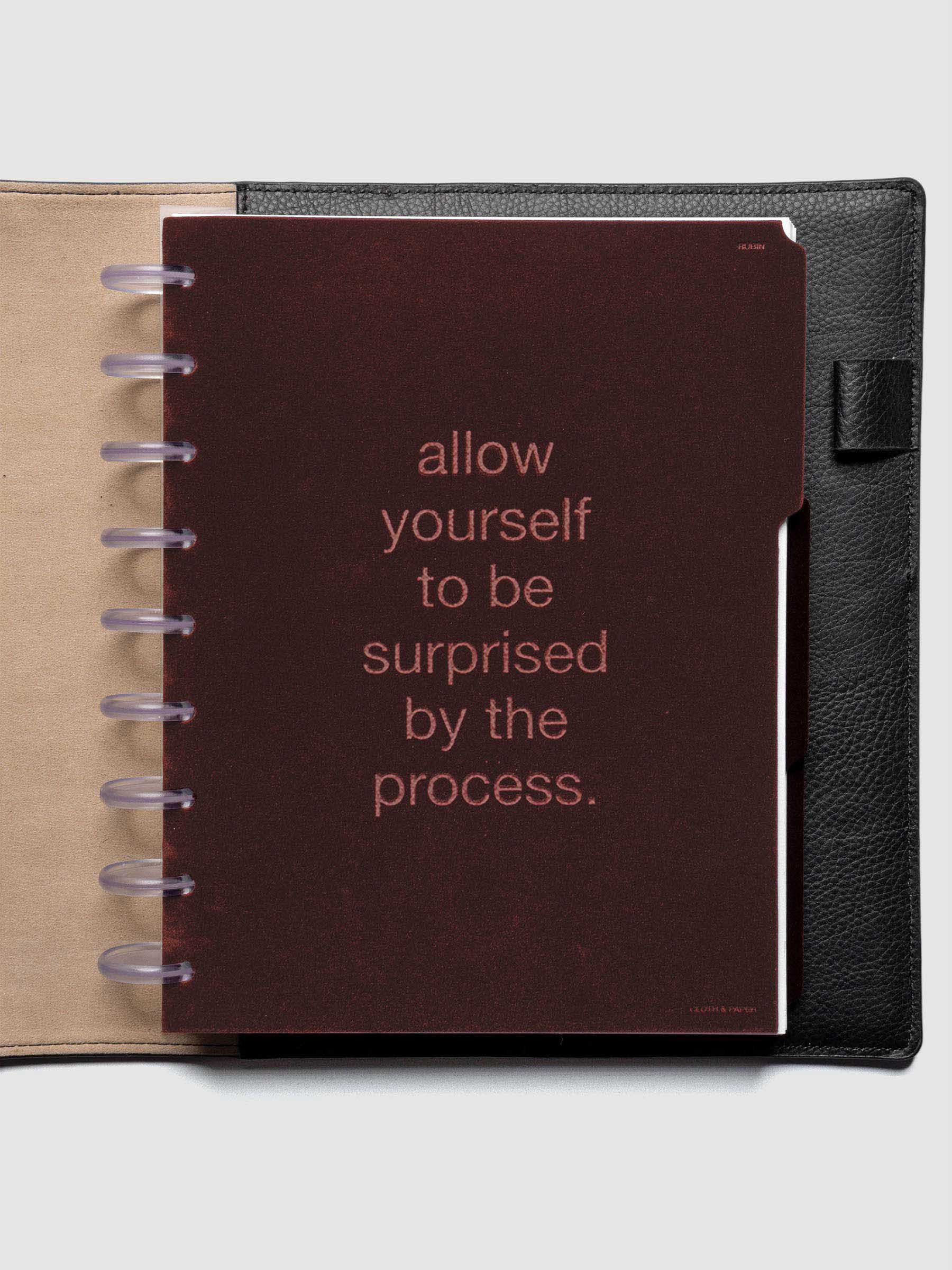 First velvet side tab planners dividers in the color Bordeaux with text deboss design reading "allow yourself to be surprised by the process" in size HP Classic shown discbound in a black leather folio.