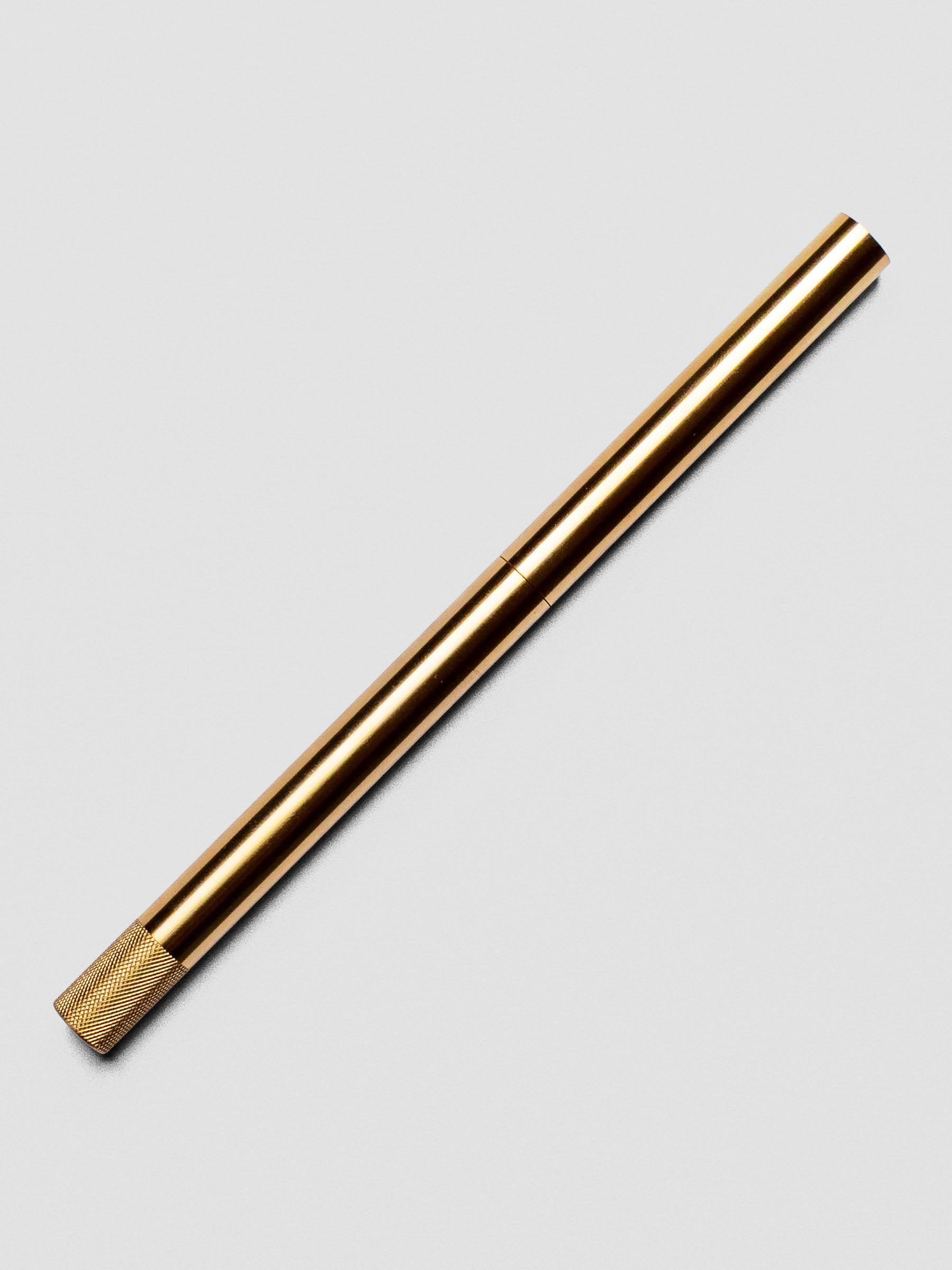 Brass Lumos Pro Duo Tip Pen resting diagonally on an open notebook, capped.