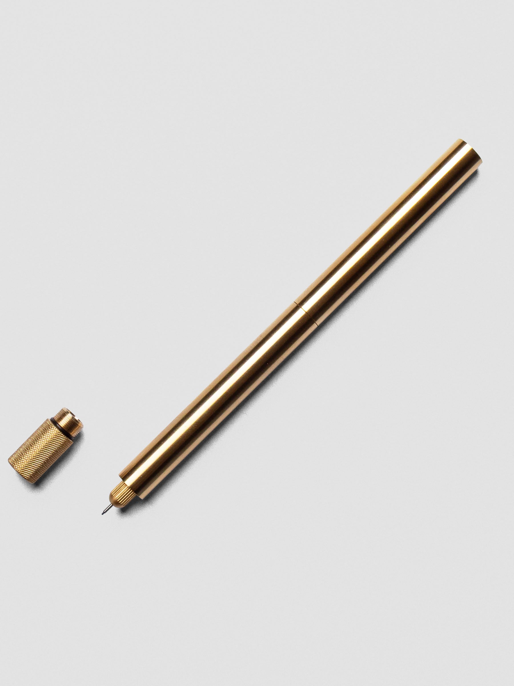 Close-up of Brass Lumos Pro Duo Tip Pen angled across a notebook page, uncapped on one ends.