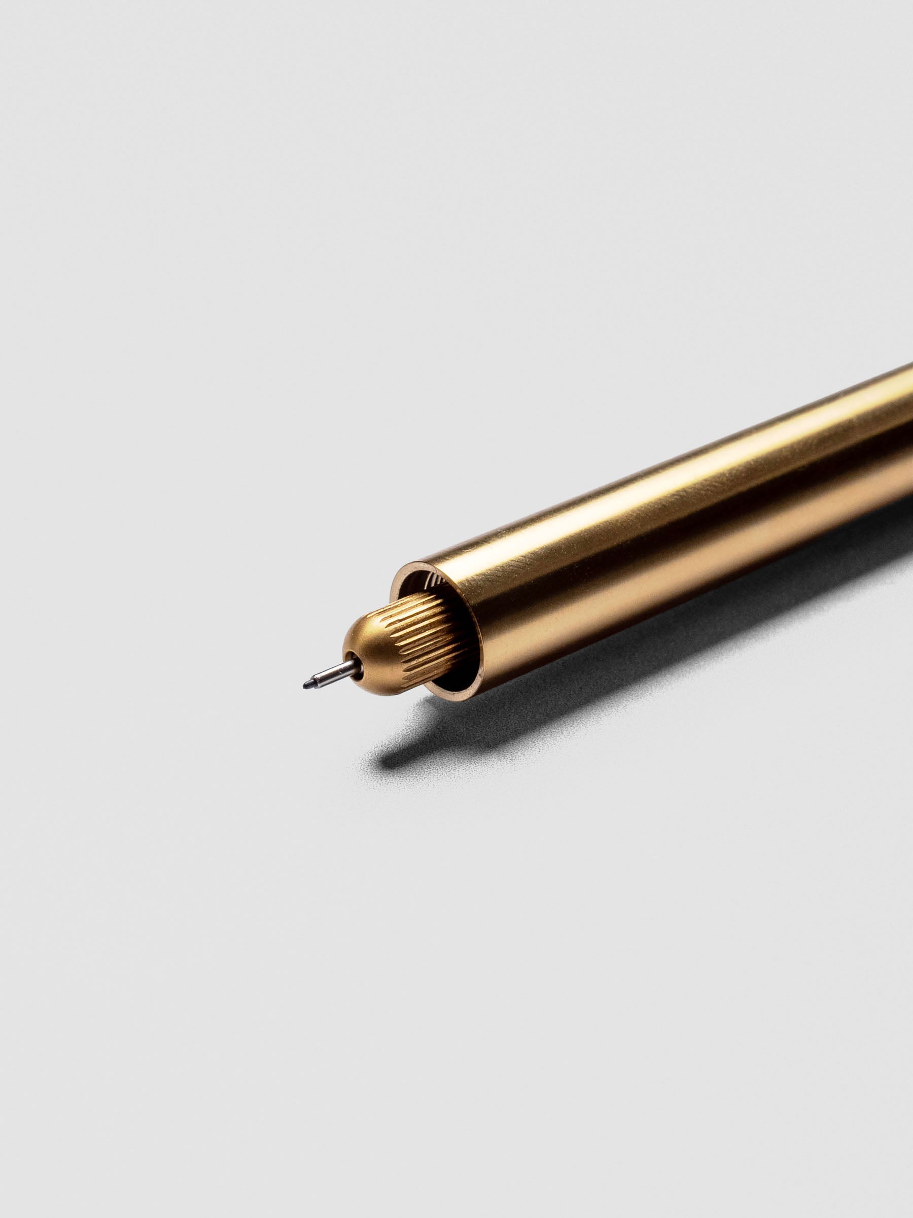 Close-up of uncapped Brass Lumos Pro Duo Tip Pen with writing tip visible.