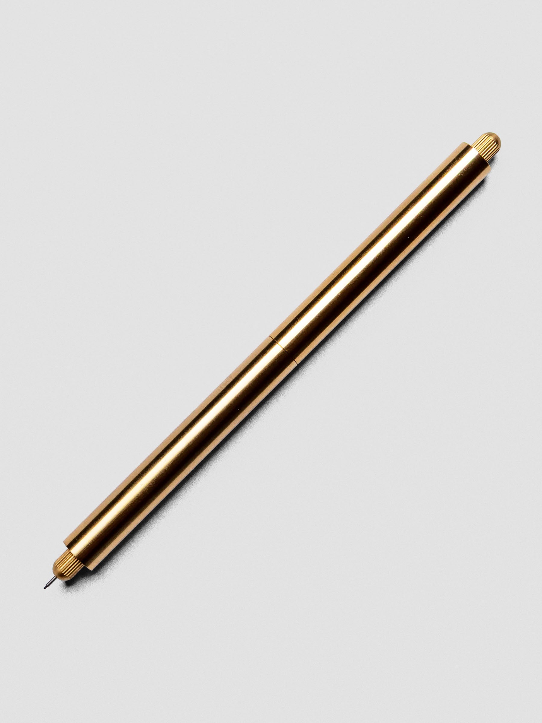Brass Lumos Pro Duo Tip Pen placed beside its cap on an neutral background.