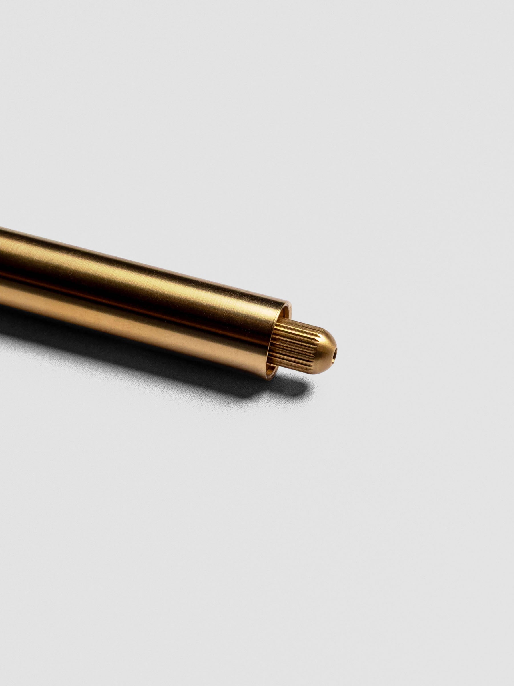 Brass Lumos Pro Duo Tip Pen resting diagonally, uncapped with no tip visible.