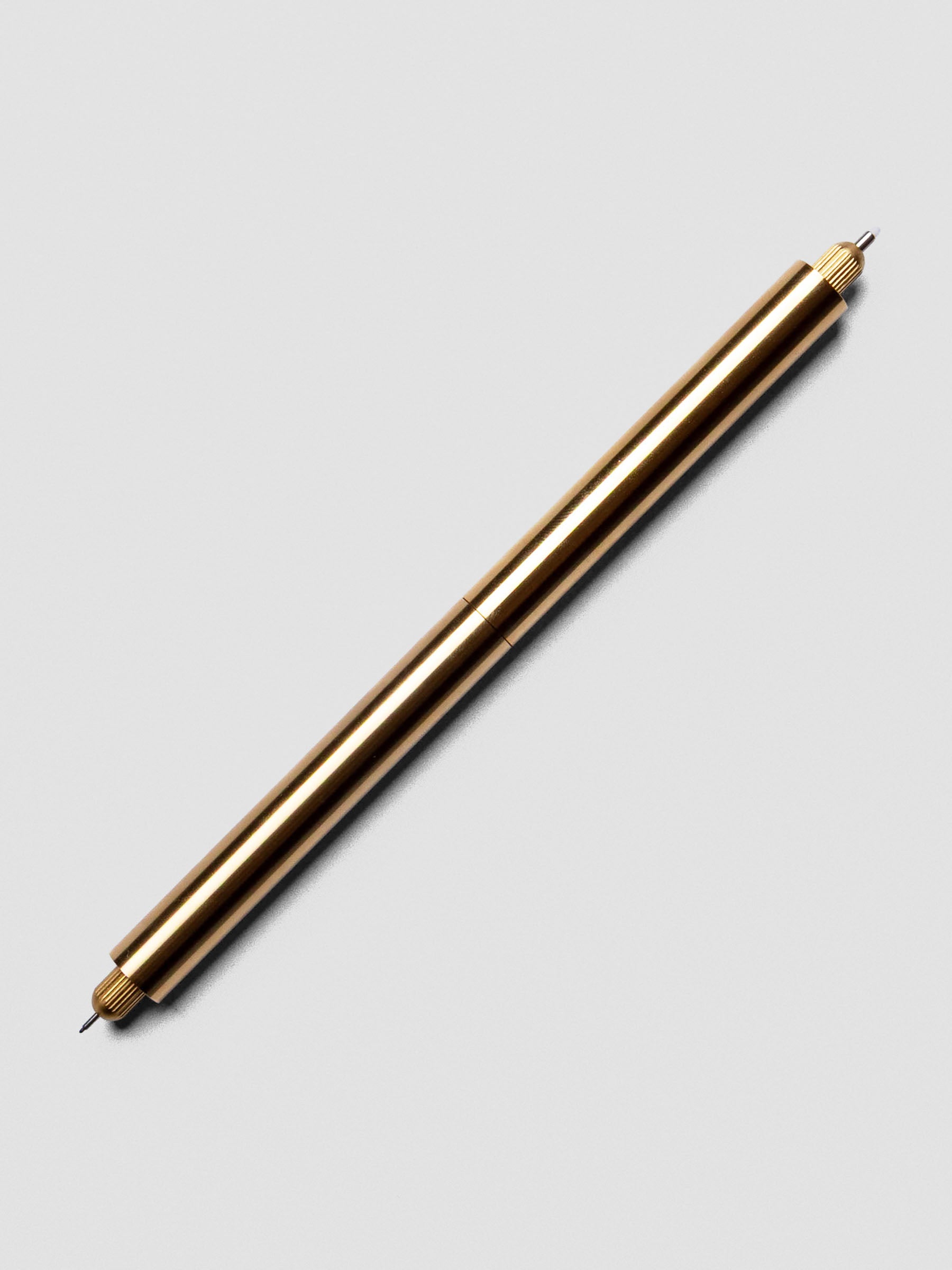 Close-up of Brass Lumos Pro Duo Tip Pen angled across a notebook page, uncapped on both ends.
