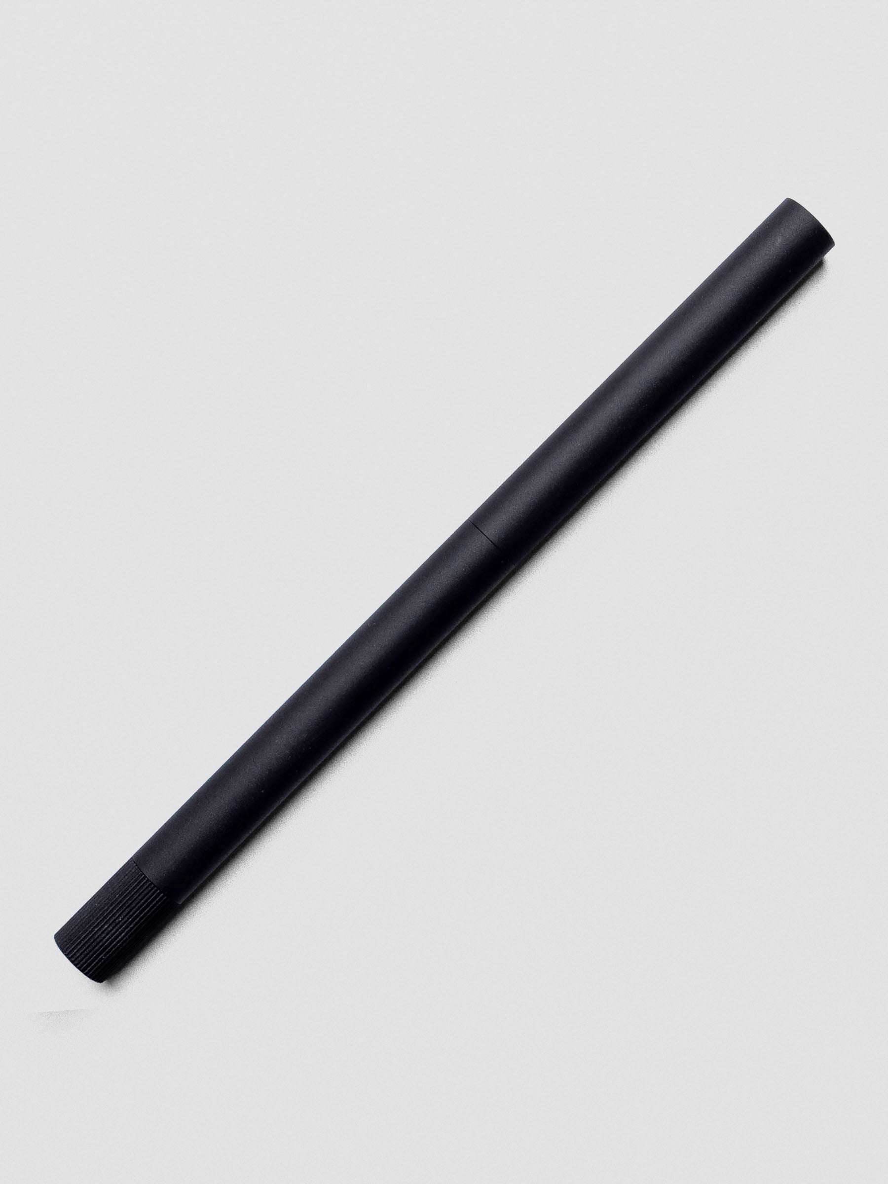 Matte Black Lumos Pro Duo Tip Pen resting diagonally on an open notebook, capped.