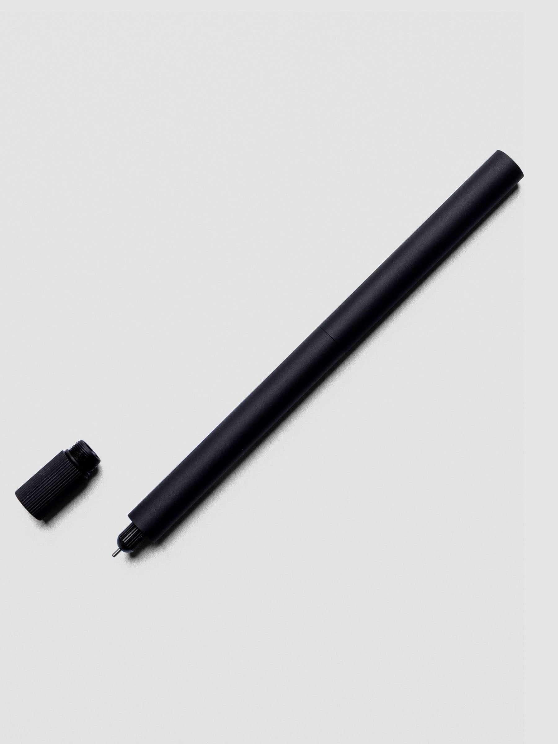 Matte Black Lumos Pro Duo Tip Pen placed beside its cap on an neutral background.