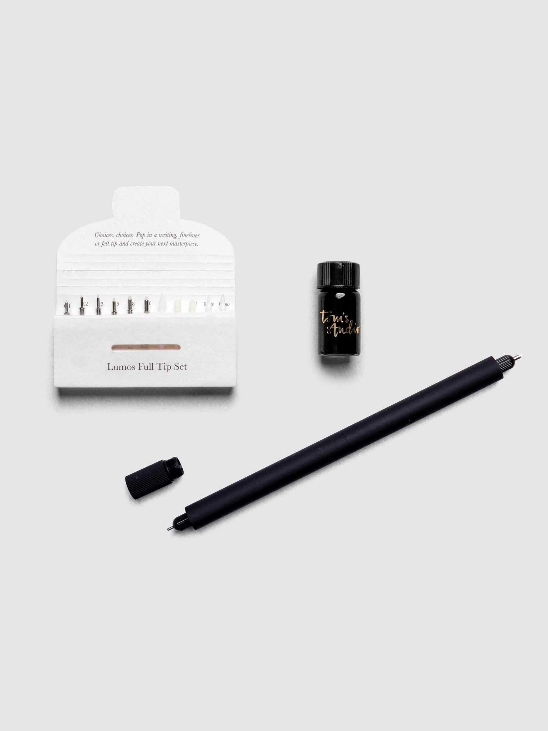 Matte Black Lumos Pro Duo Tip Pen resting diagonally on an open notebook, uncapped, shown with tips set and ink.