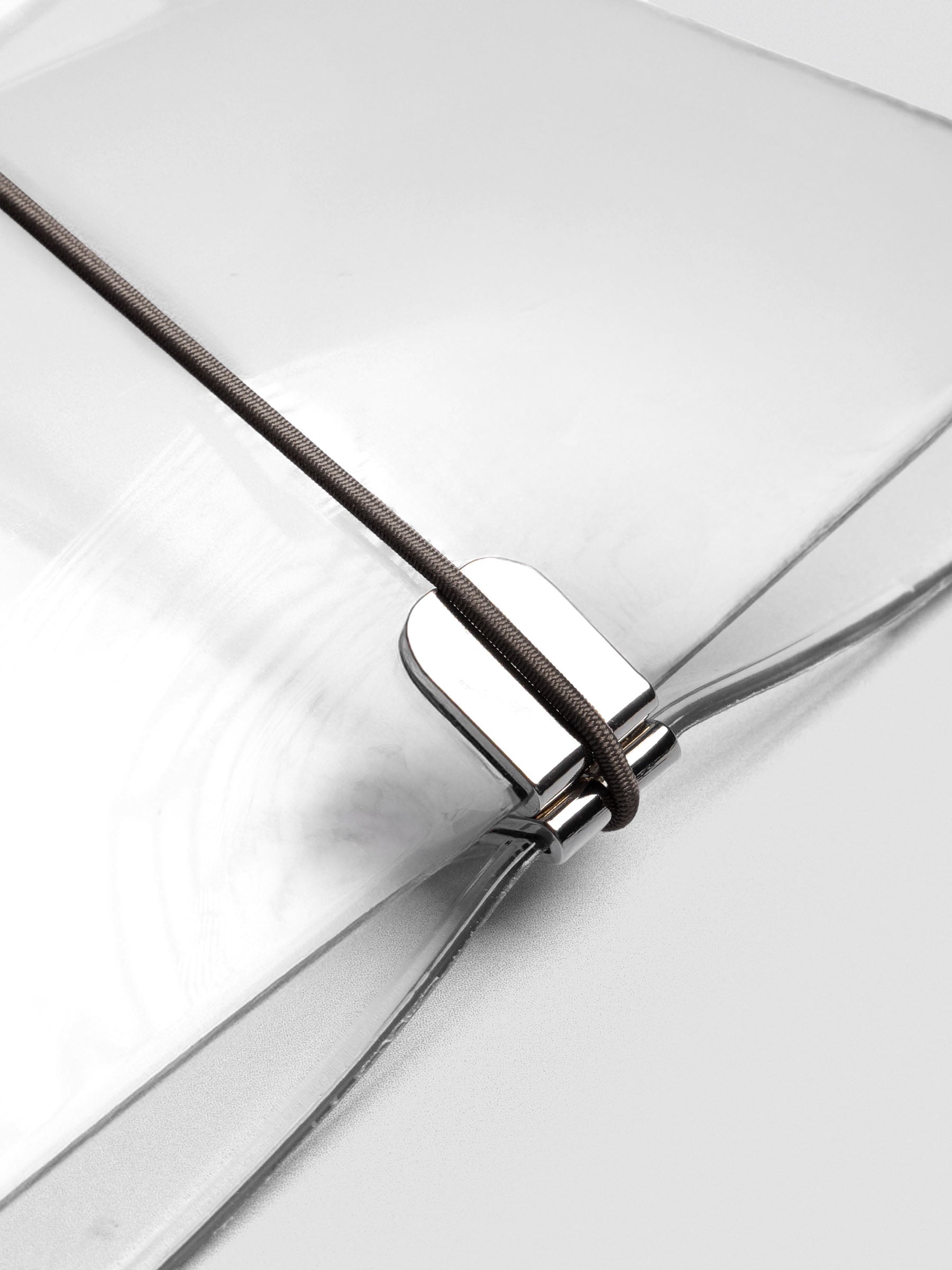 Dark brown elastic band stretched across a clear vinyl travel cover, anchored at the metal clasp.