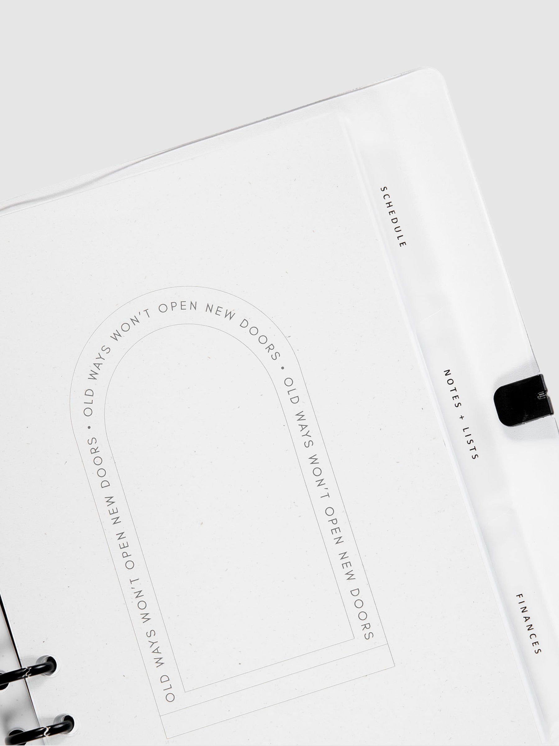 The Essentials Side Tab Planner Dividers, Glass Plastic, Black Text, Cloth and Paper. Dividers inside a planner turned slightly to the left against a neutral background.