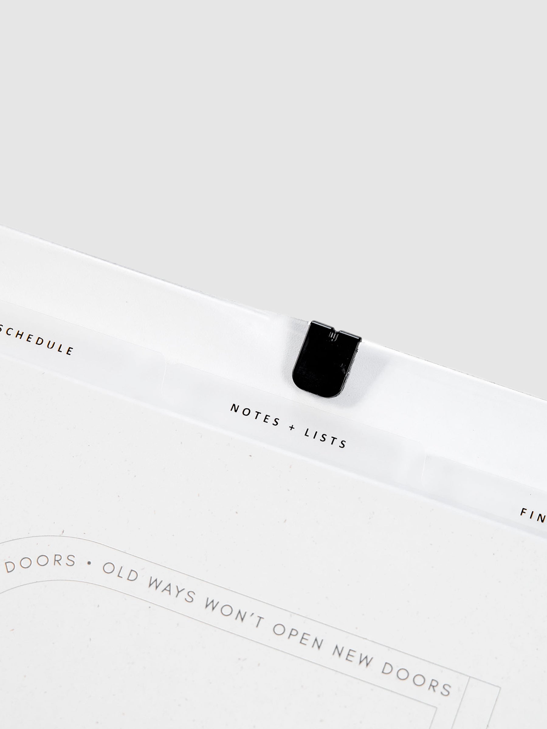 The Essentials Side Tab Planner Dividers, Glass Plastic, Black Text, Cloth and Paper. Close up on dividers inside planner against a neutral background.