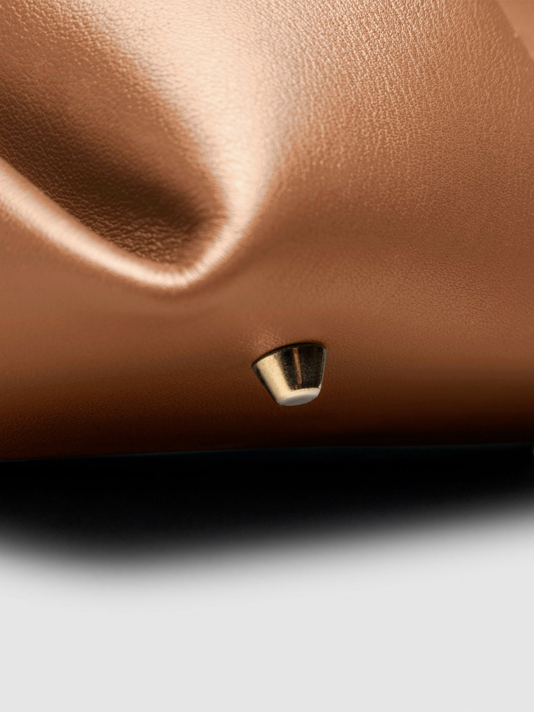 Closeup of the gold feet on the bottom of the bag. Color shown is Alhambra.