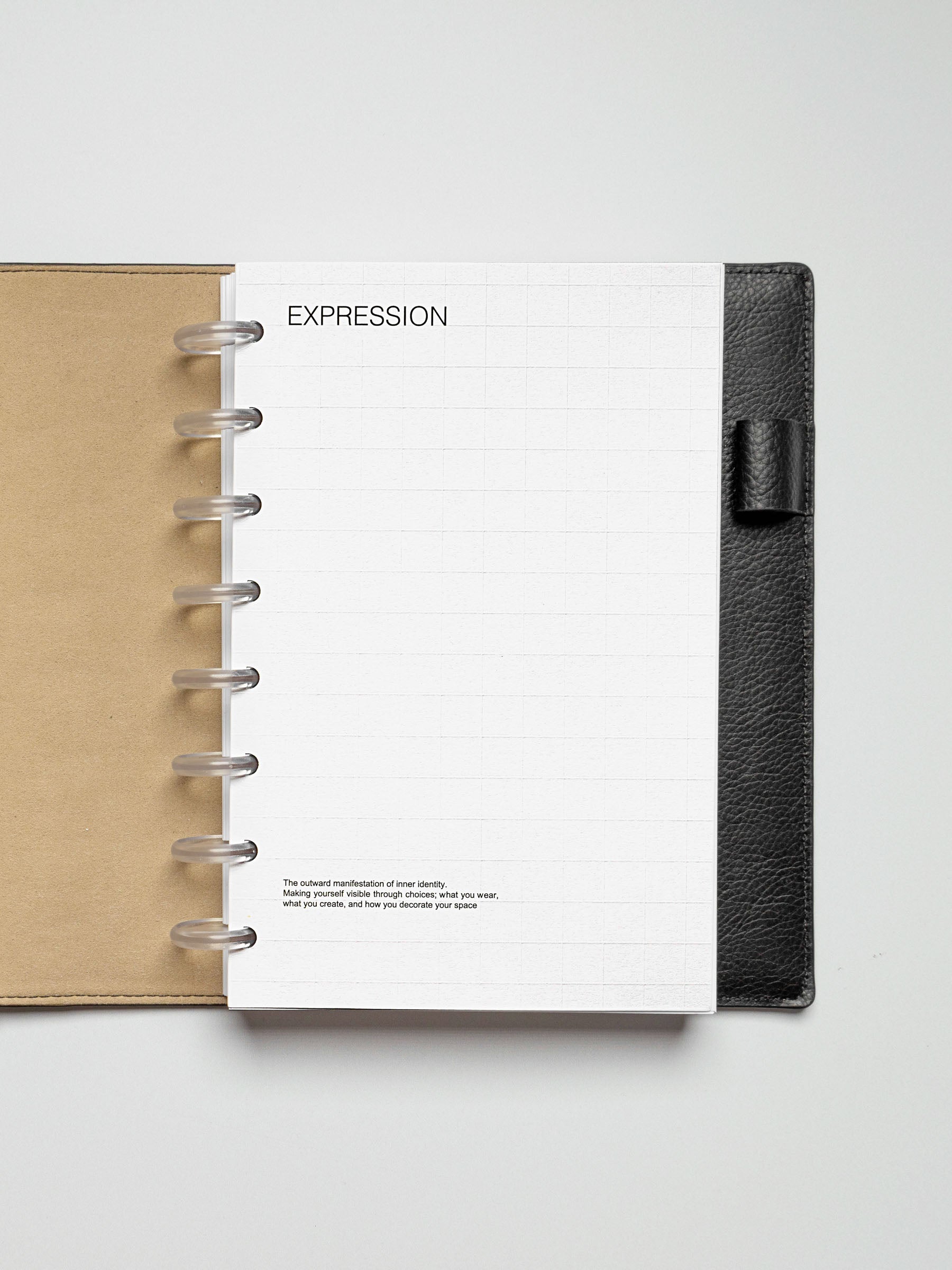 Half Letter Tile Planner Dashboard displayed in a black leather disc-bound planner, featuring a grid pattern and "EXPRESSION" header.