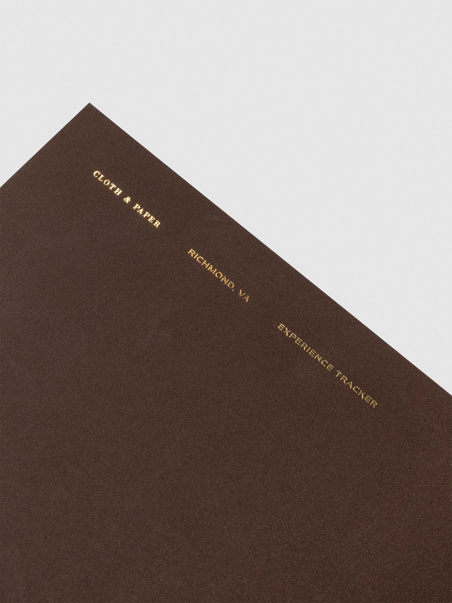 Close-up of the Travel Notebook | A5 Slim - Experience Tracker in Walnut, highlighting the gold foil-stamped text: "Cloth & Paper, Richmond VA, Experience Tracker."
