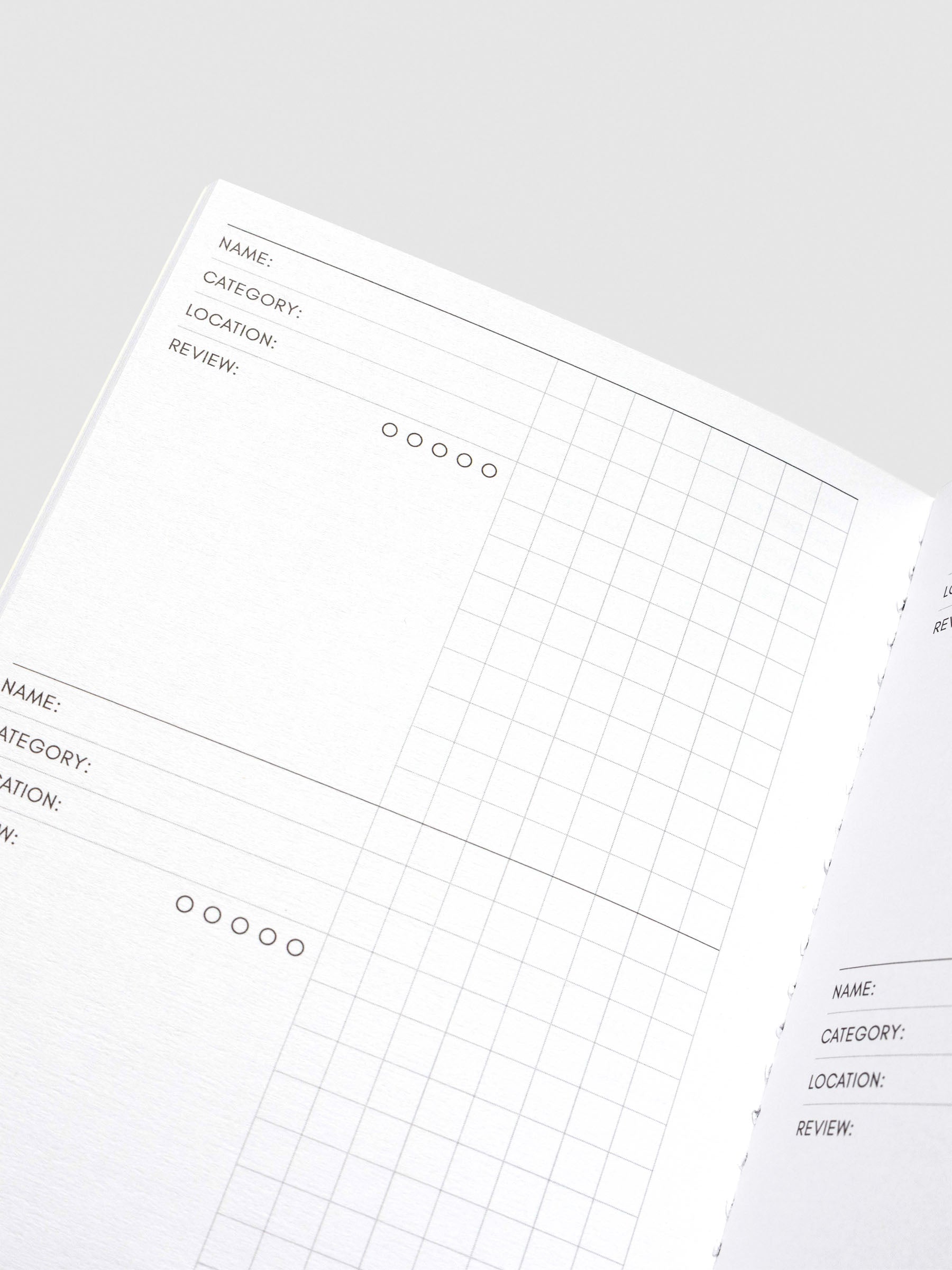 Interior view of the Experience Tracker notebook, showing structured pages with sections for Name, Category, Location, Review, a 5-star rating scale, and a gridded notes area.