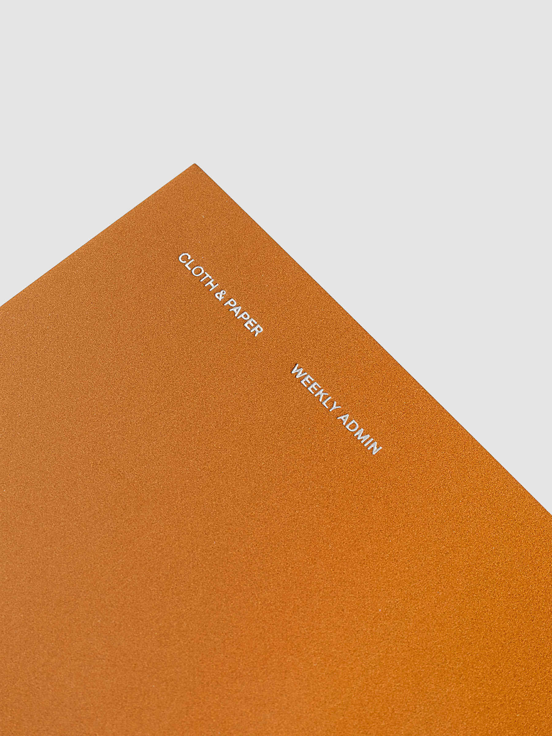 Close up of the top left of the Weekly Admin Pocket Plus travel notebook with silver foil cover text, displayed on a neutral background