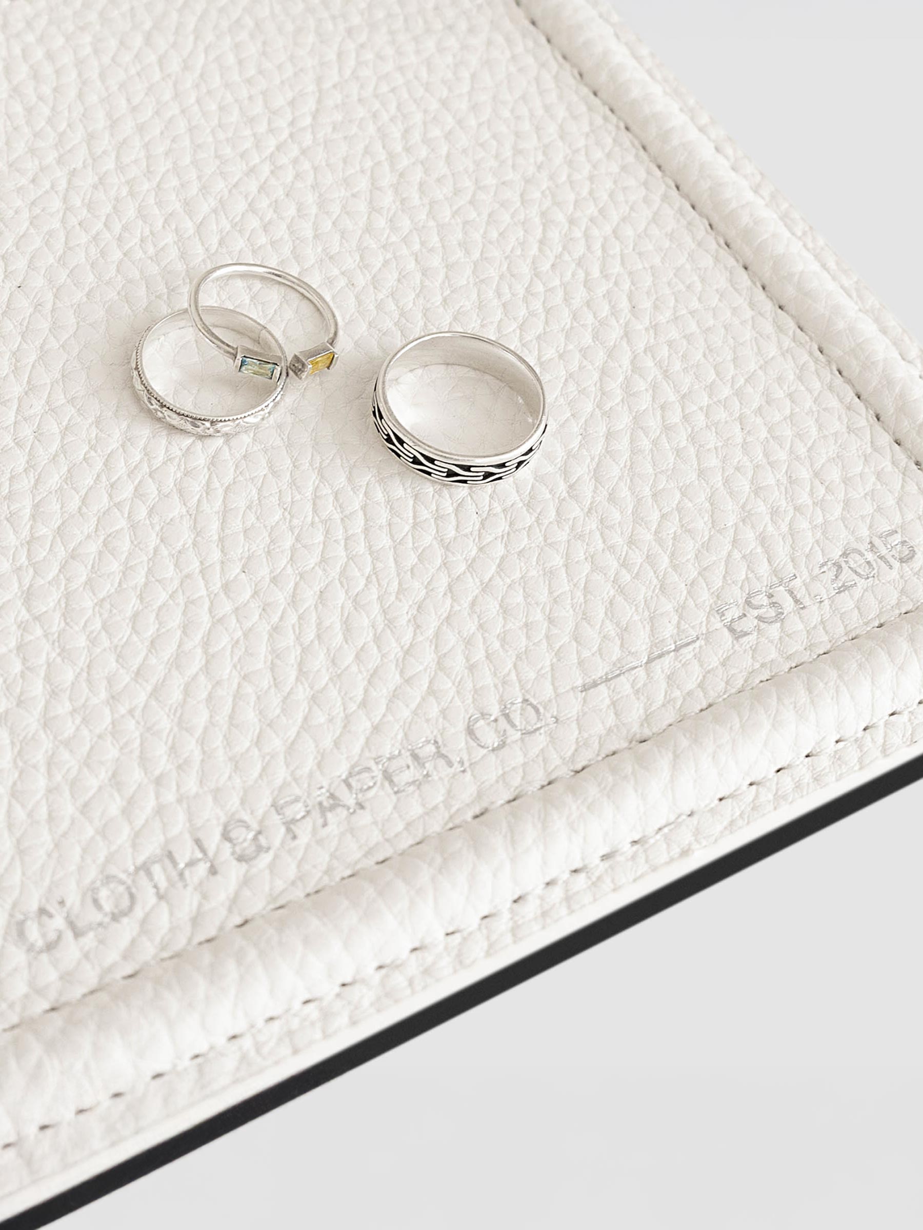 Closeup of tray shown with three silver rings displayed inside it.