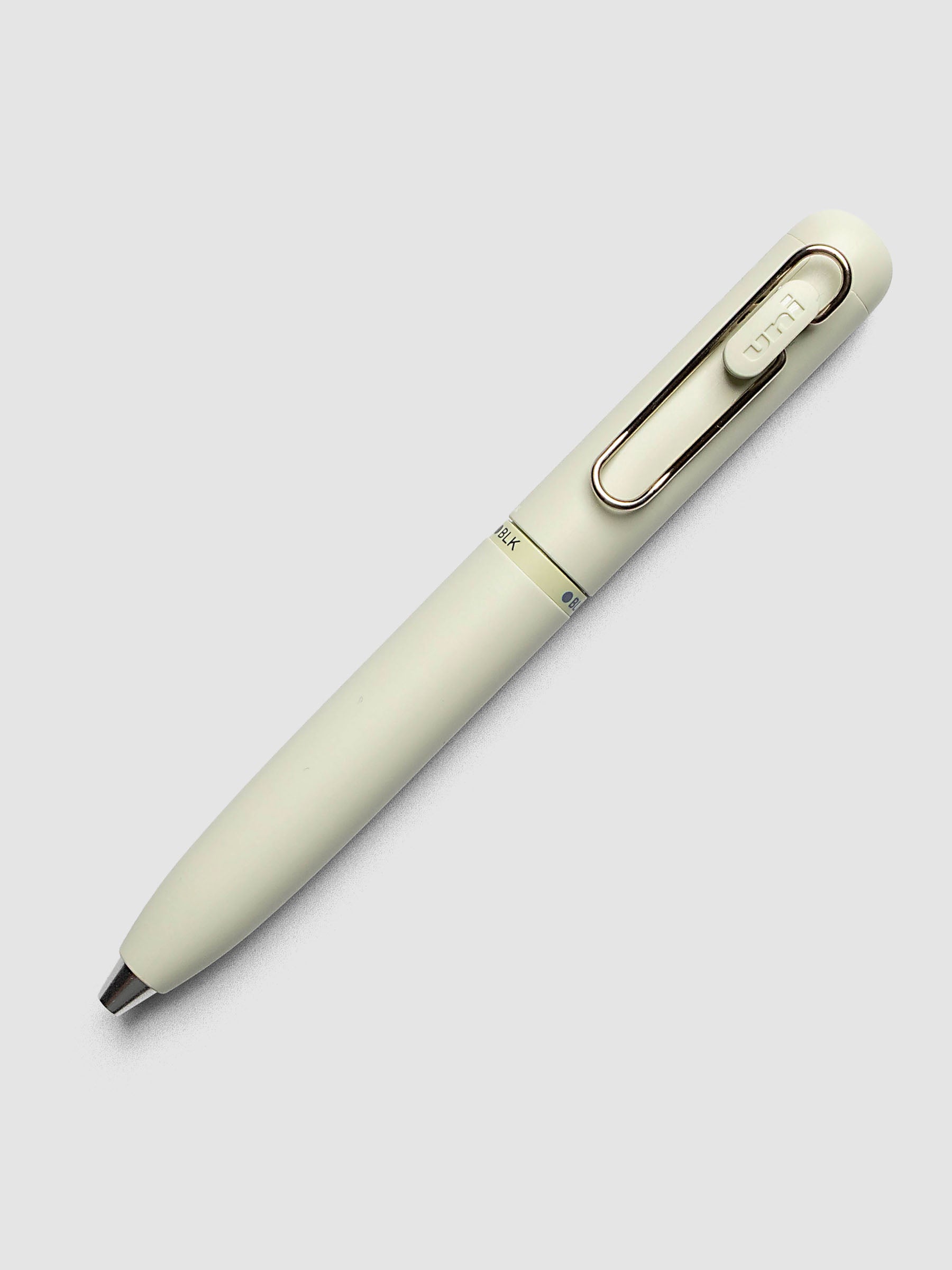 Uni-ball One 3-Color Ballpoint Pen in pale sage green laid diagonally showing clip and BLK color indicator