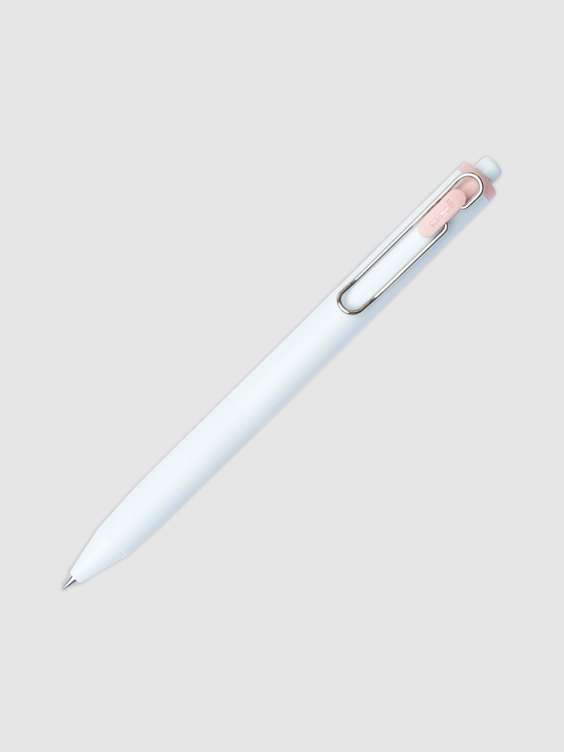 Uni-ball One Gel Pen, Peach Canele, Cloth and Paper. Pen tilted slightly to the right on a neutral background.