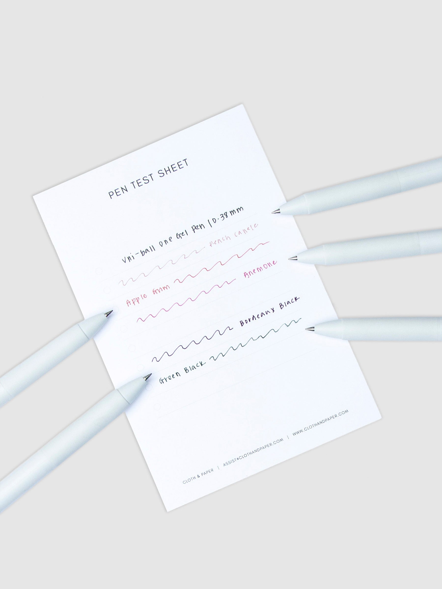 Pen test sheet showing ink samples for Powder Snow, Blue Colon, Denim Blue, Pansy, and Sumire ink. Five pens are resting on the edges of the pen test sheet.