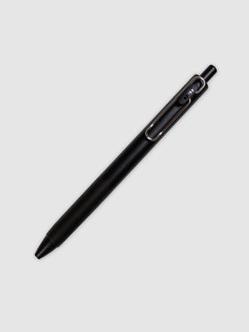 Uni One Gel Pen, 0.38 mm, Black Ink, Black Barrel, Cloth and Paper. Pen turned to the right against a neutral background.