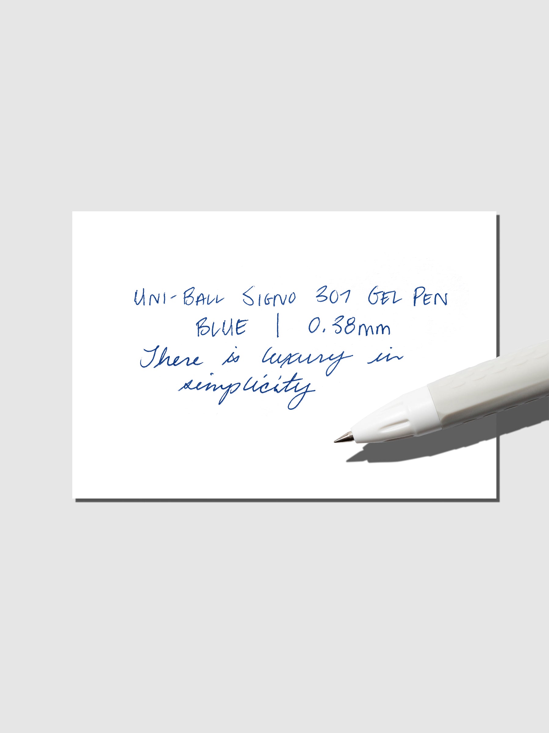 Uni-Ball Signo Gel pen resting on a pen test sheet. The sheet shows the pens specs. Color pictured is Blue.