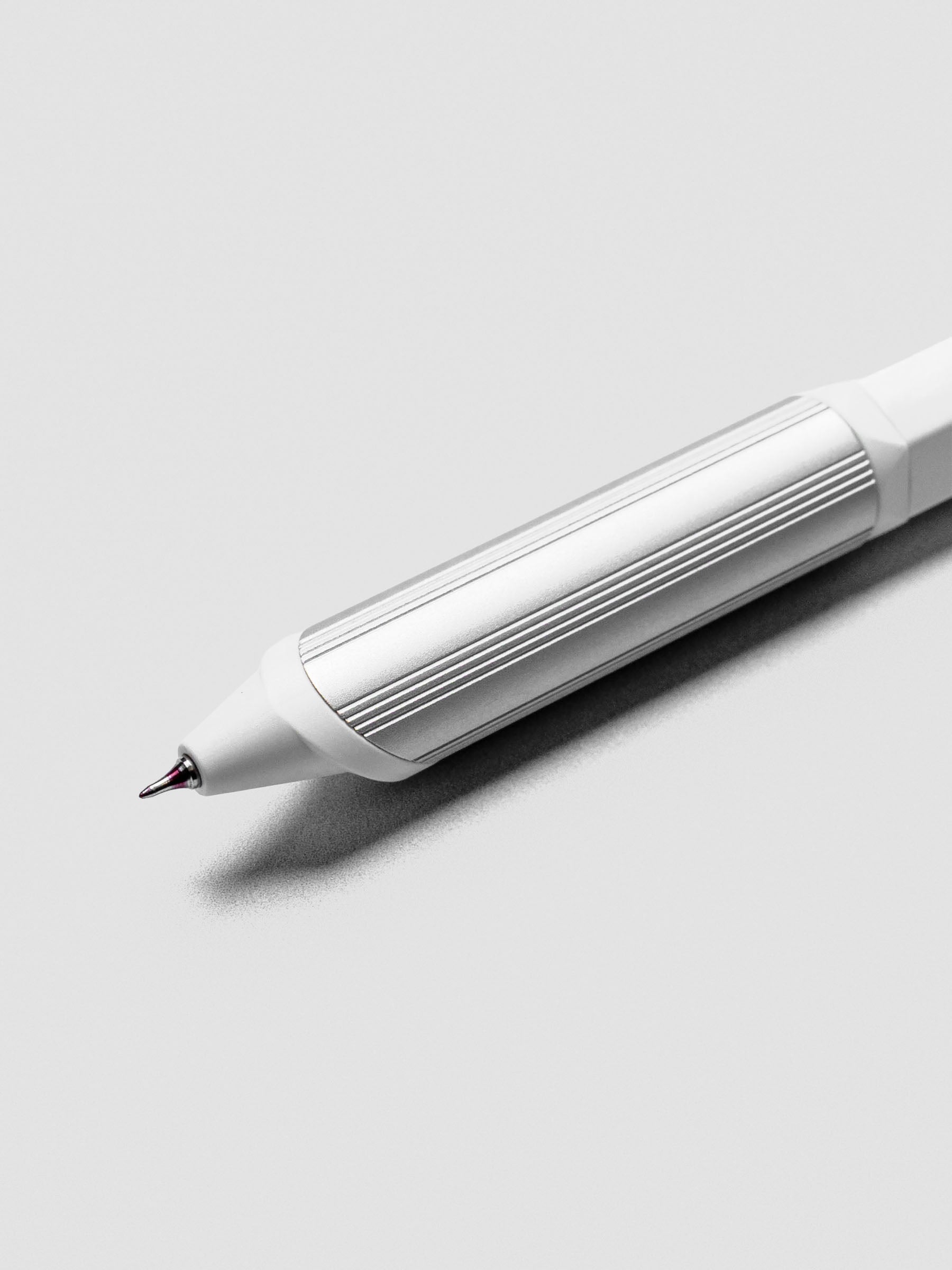 Close up of a ballpoint multi-pen's red ink tip with a white barrel and silver grip.