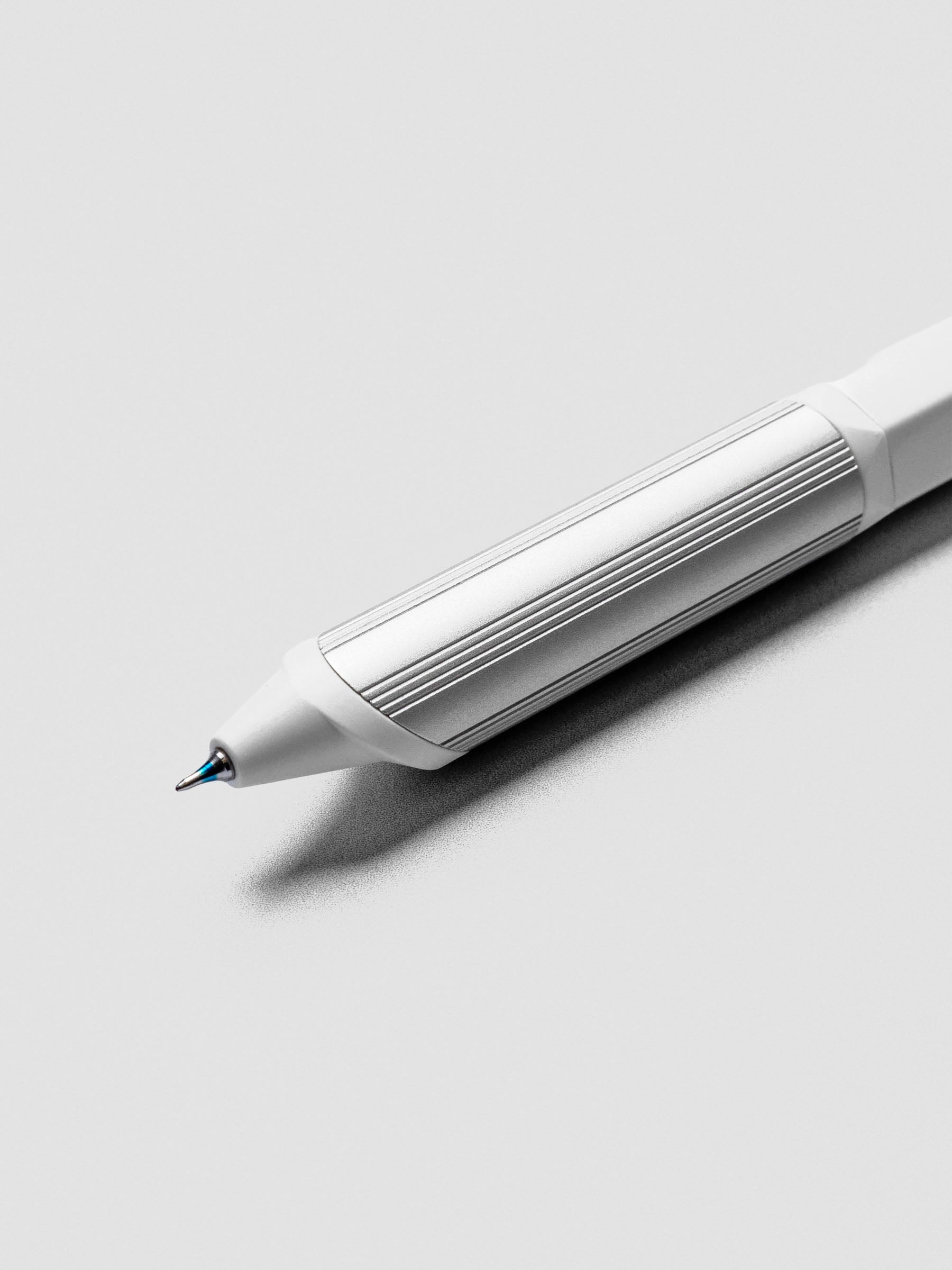 Close up of a ballpoint multi-pen's blue ink tip with a white barrel and silver grip.