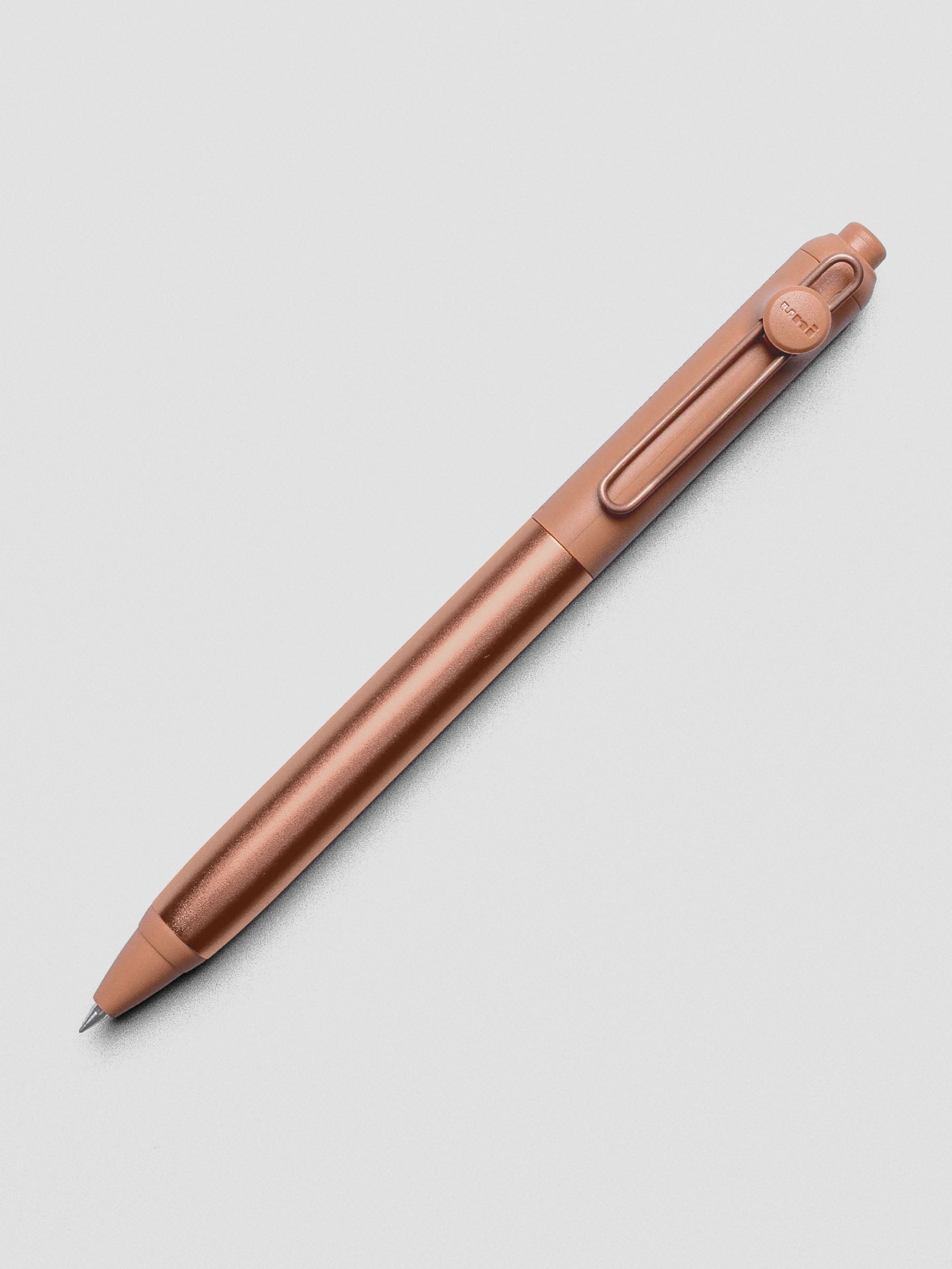 Copper colored pen shown at an angle on a grey background.