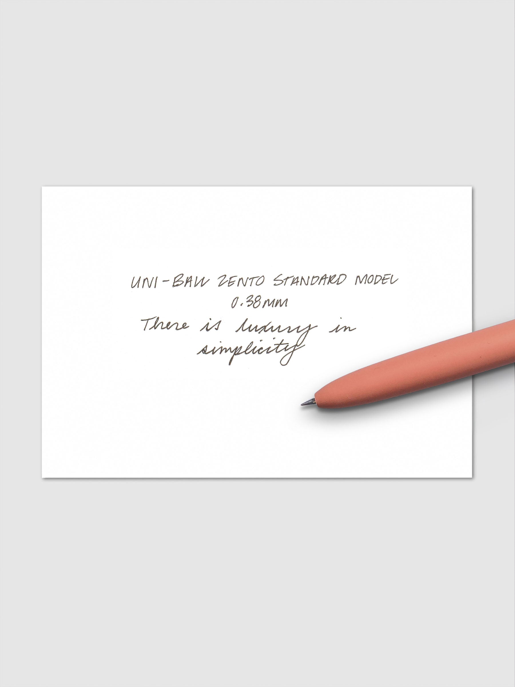 Handwritten sample using the Uni-ball Zento Standard Model Pen with black ink and a 0.38 mm nib. Shown with adobe pen resting across paper.