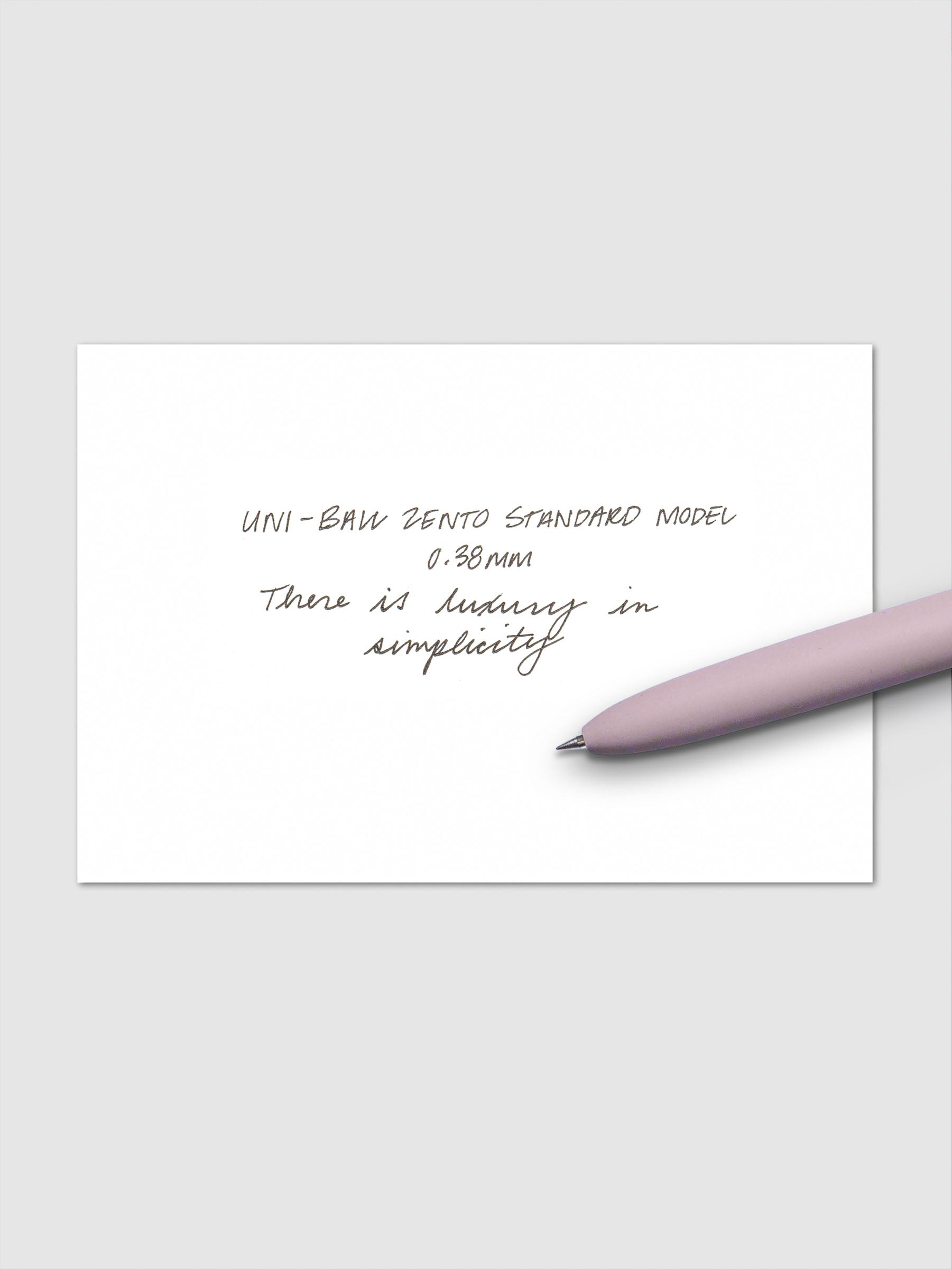 Handwritten sample using the Uni-ball Zento Standard Model Pen with black ink and a 0.38 mm nib. Shown with lavender pen resting across paper.