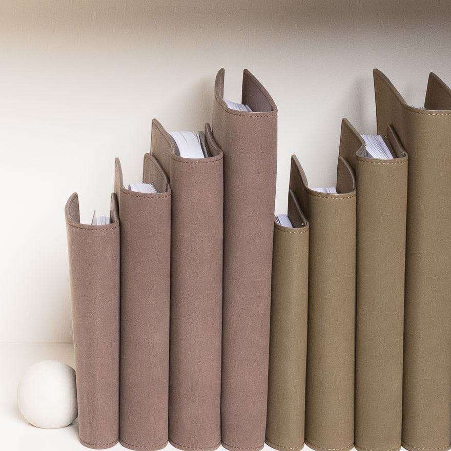 Various sizes of Vegan Leather Folios on a white bookshelf.