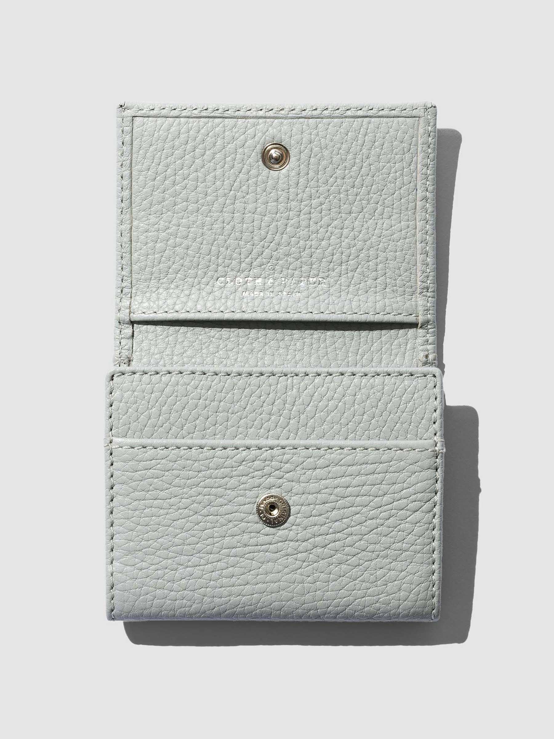 Leather wallet opened on a neutral background. Three internal pockets are visible.