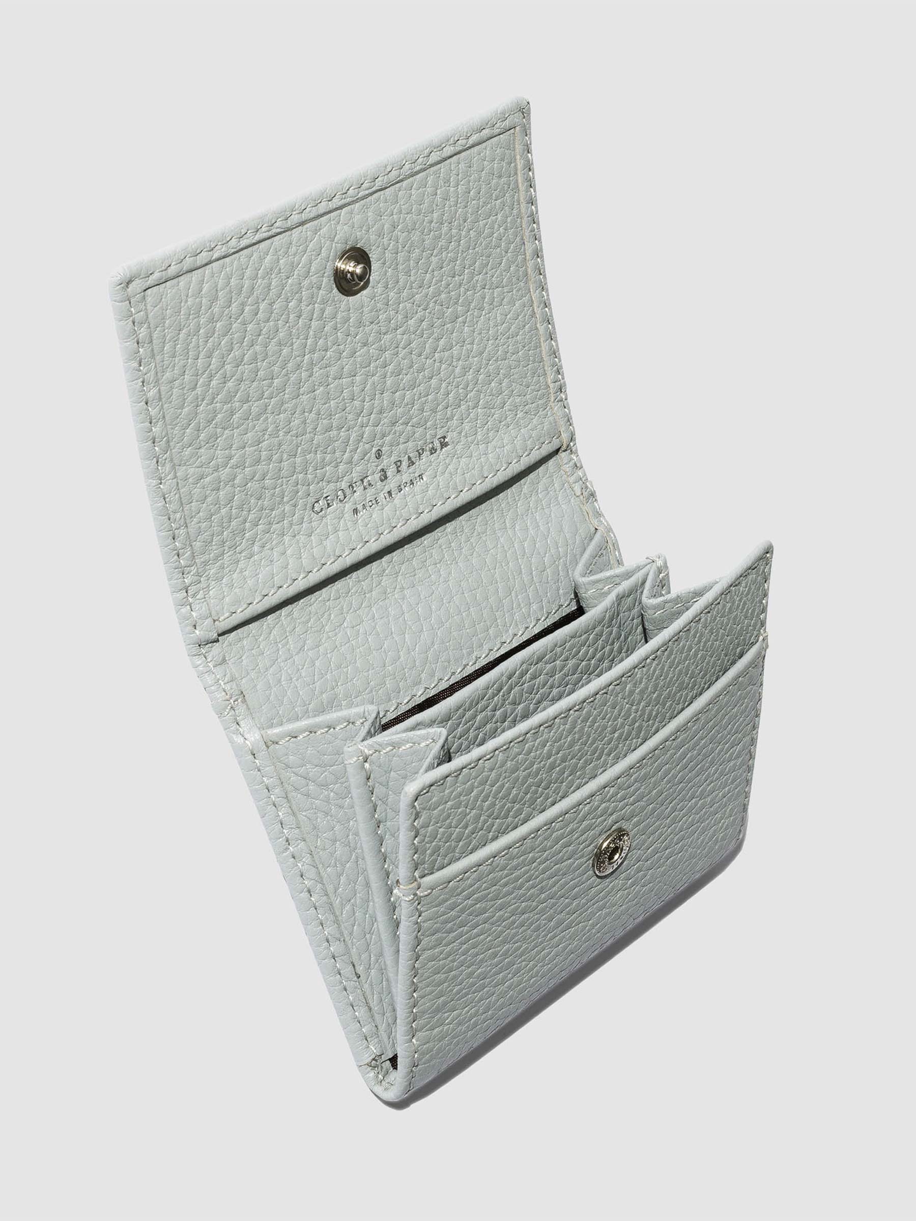 Leather wallet opened on a neutral background. Four internal pockets are visible.