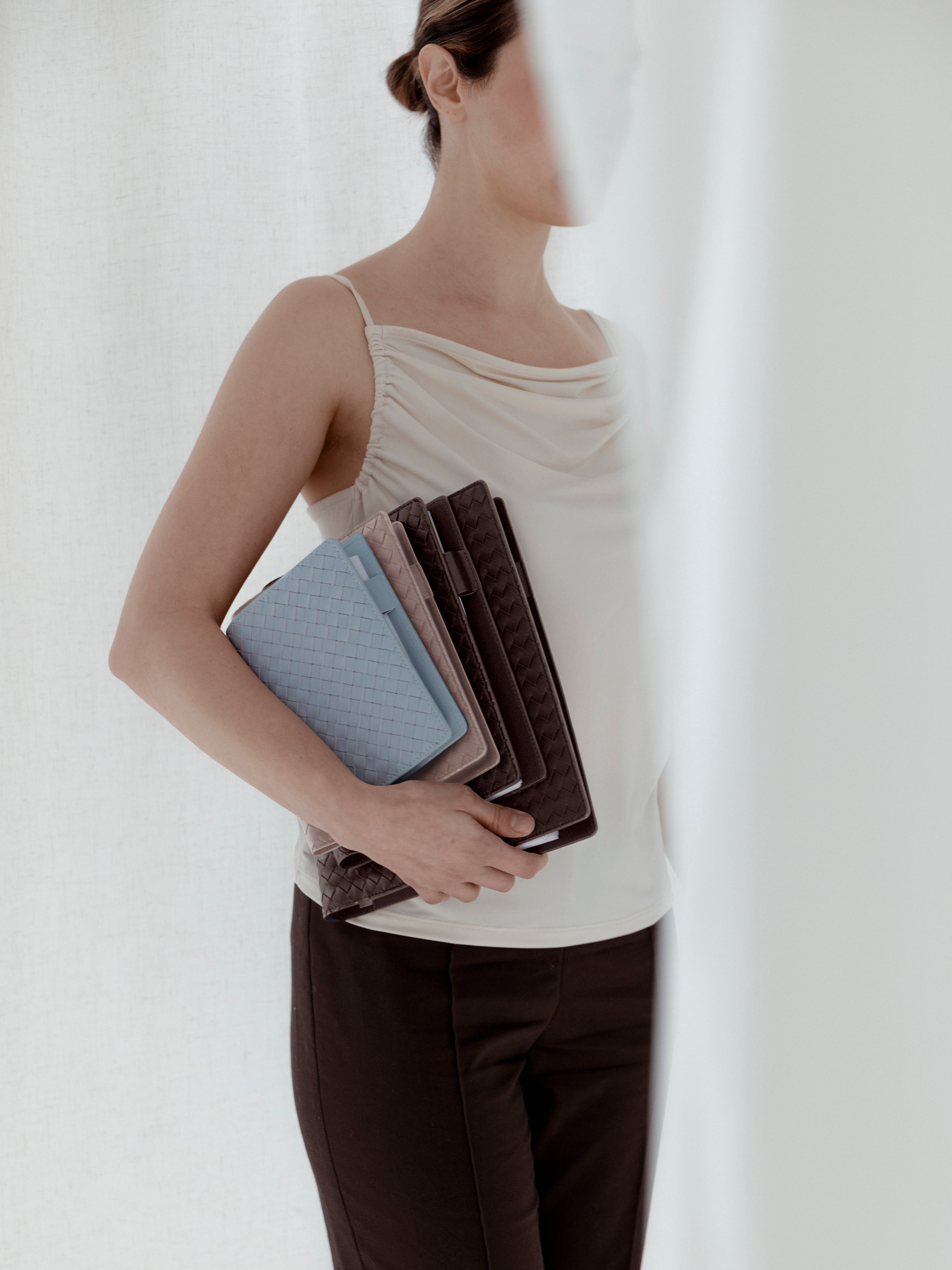 Woman holding a small, large, and HP Classic woven planner cover in the colors blue, beige, and brown.