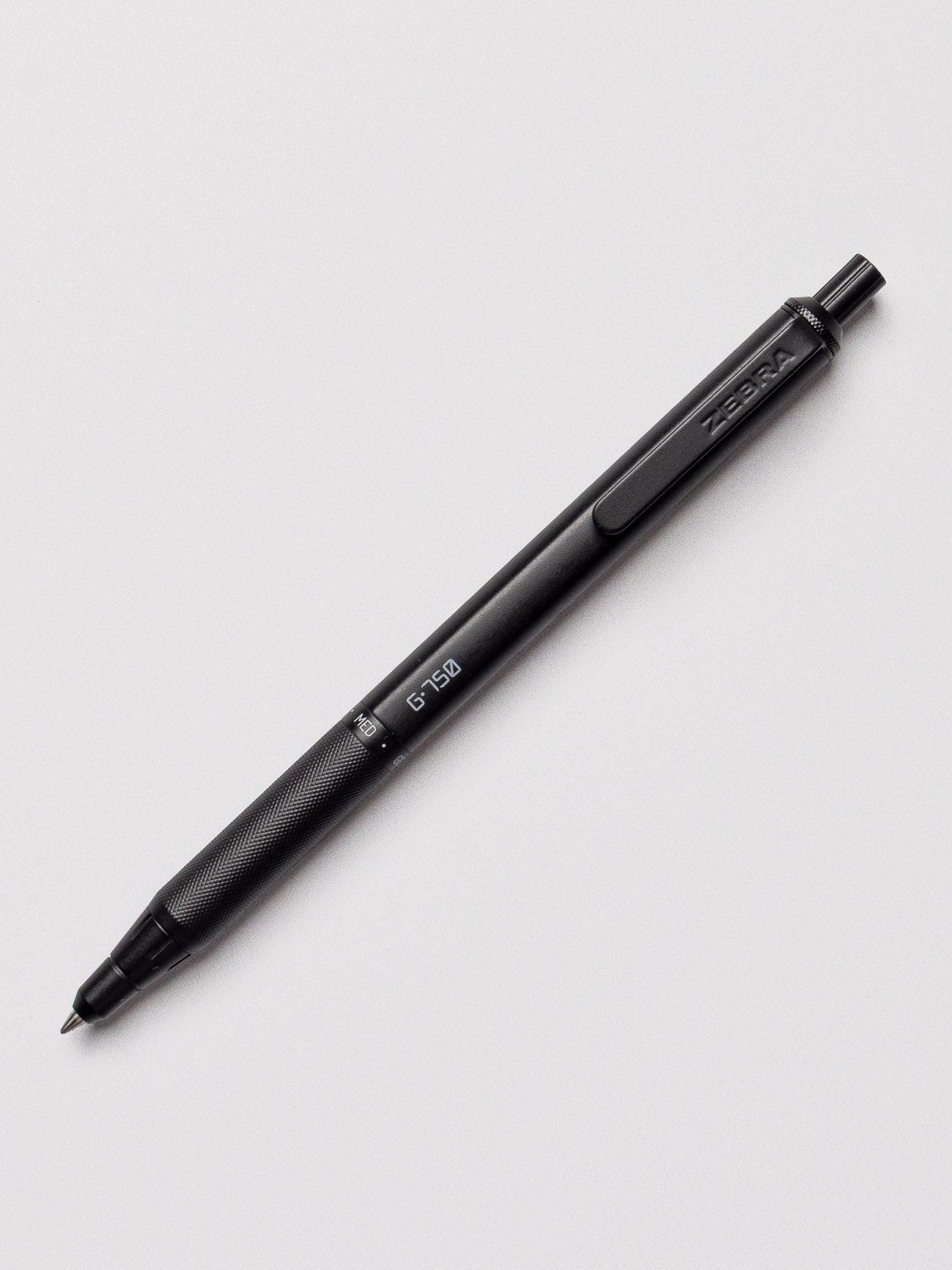 Close-up of the Zebra G-750 Retractable Gel Pen in black barrel, with the nib extended on a light gray background.
