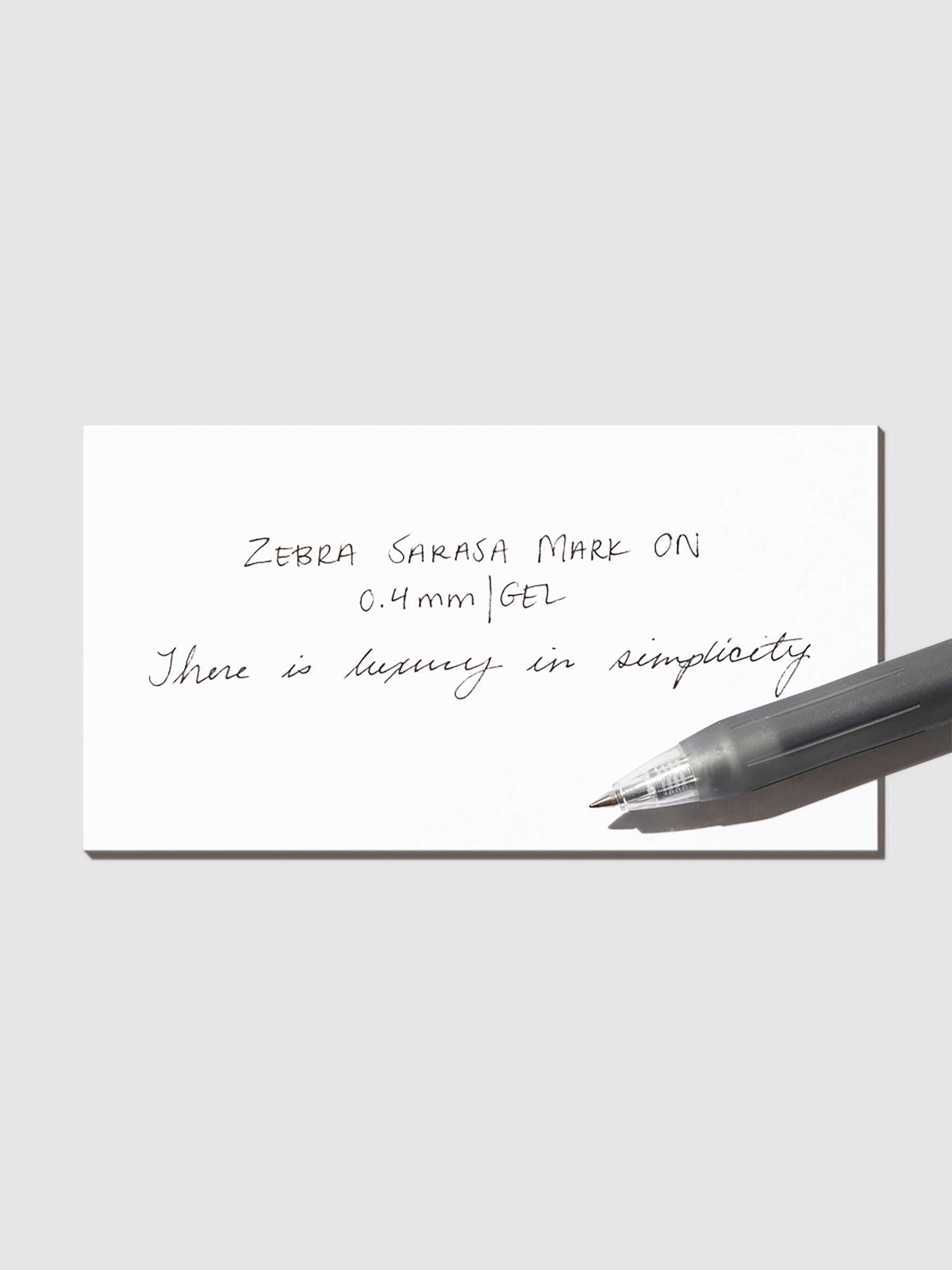 Pen in Black resting on a pen test sheet displaying a writing sample detailing the pen's specs.