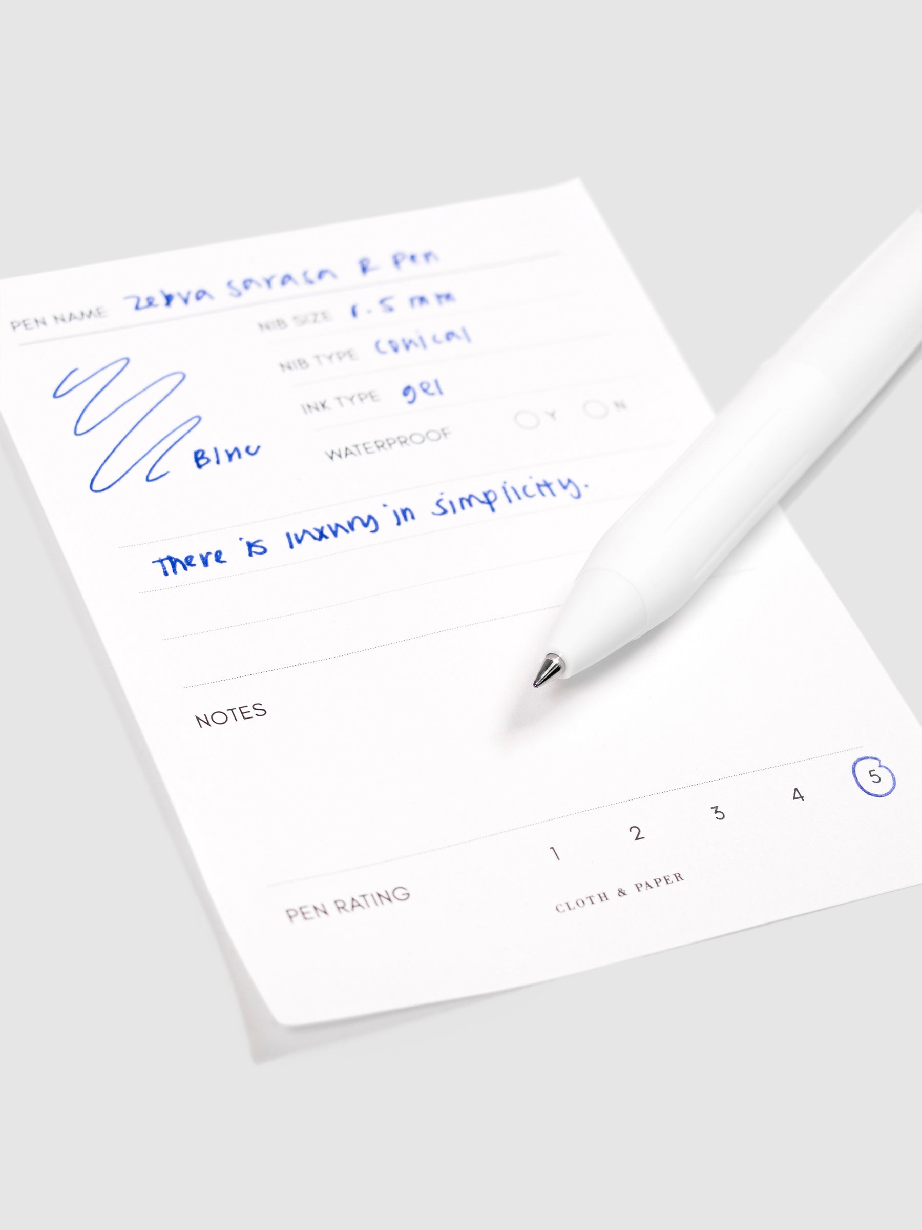 Zebra Sarasa R Pen, 0.5 mm, Blue, Cloth and Paper. Close up on pen nib resting on pen test sheet.