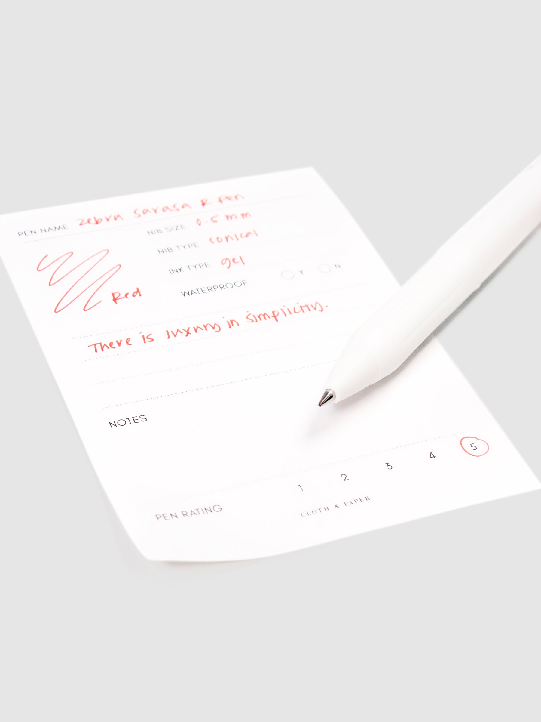 Zebra Sarasa R Pen, 0.5 mm, Red, Cloth and Paper. Close up on pen nib resting on pen test sheet.