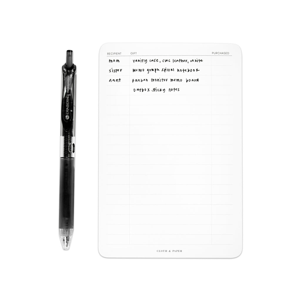 Gift List Notepad, Cloth and Paper. Notepad styled with writing on it and pen perpendicular to it, against a white background.