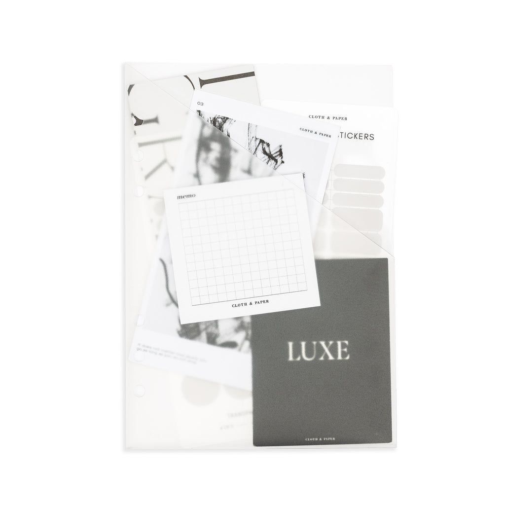 Folder in use on a white background. Inside the pocket are several journaling cards, stickers, and sticky notes.