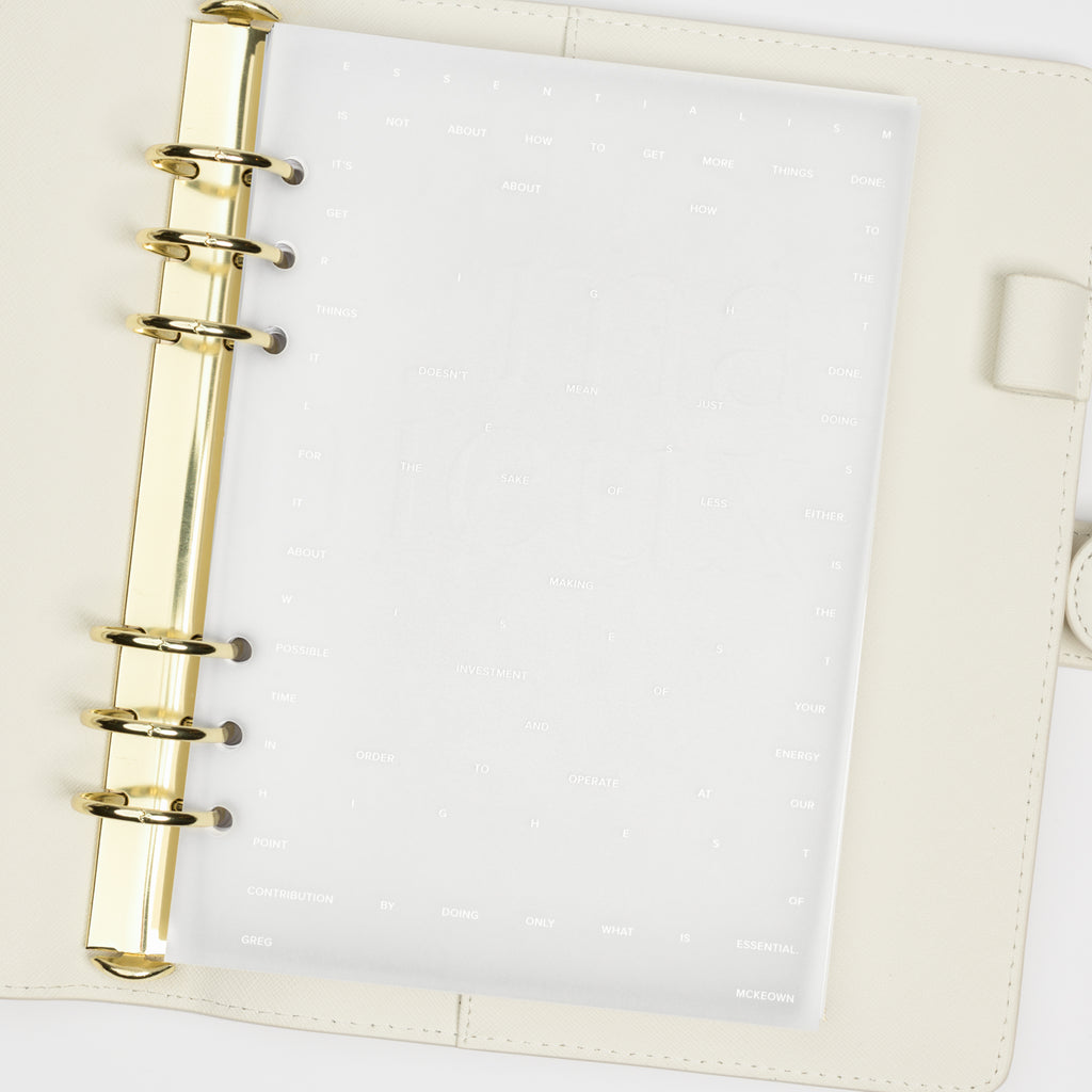 Dashboard duo in use inside a white leather planner. The transparent vellum dashboard is layered over a blank white sheet of paper.