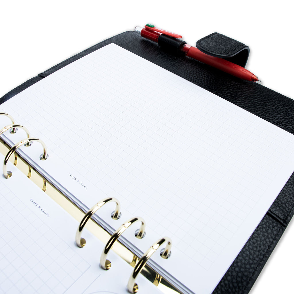 Creative Planning Insert Bundle, Cloth and Paper. Close up image of inserts in use inside a black leather agenda with gold rings. A pen rests in the agenda's pen loop. Pictured insert page shows graph notes. 