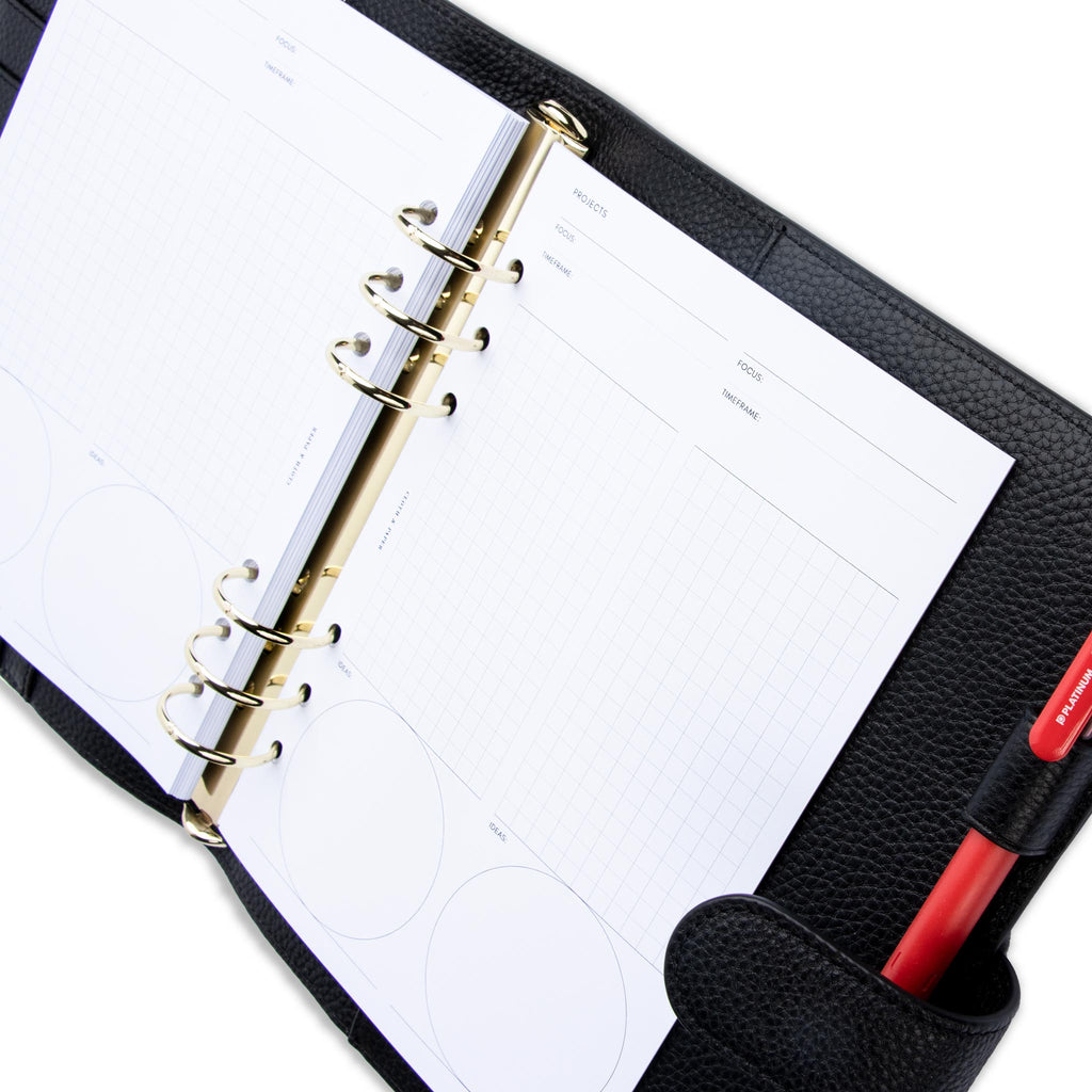 Creative Planning Insert Bundle, Cloth and Paper. Inserts in use inside a black leather agenda with gold rings. A red pen rests in the agenda's pen loop. Inserts shown are two Project pages.