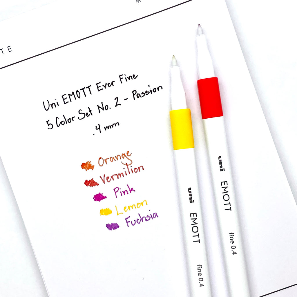 Uni EMOTT Ever Fine, 5 Color Set No. 2, Passion, Cloth and Paper. Two pens resting on paper displaying a writing sample.