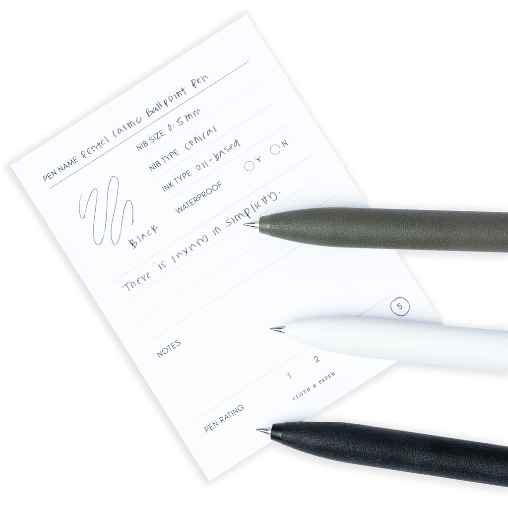 All three color options of the pen resting on a pen test sheet displaying a writing sample detailing the pen's specs.